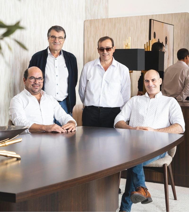 Elementos da equipa de logística reunidos em redor de uma mesa de reuniões, fundamentais para a execução e entrega de projetos de design de interiores, excelência em interior design e serviços de decoração.
