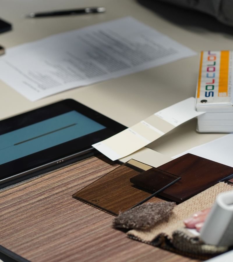 Mesa de trabalho do departamento de marketing com catálogo de cores, tablet e paleta de acabamentos, planeando a comunicação de projetos de design de interiores, referências de interior design e serviços de decoração.