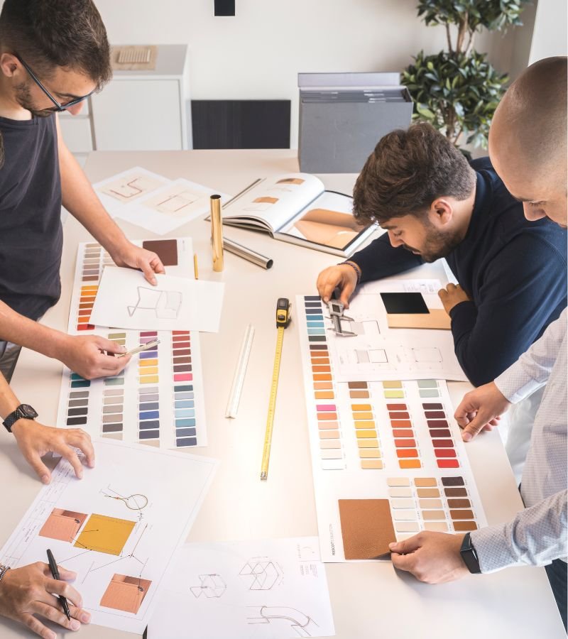 Equipa do departamento técnico a analisar amostras de tecidos, cores e esboços, assegurando o rigor de design de interiores e interior design em projetos e serviços de decoração de luxo.