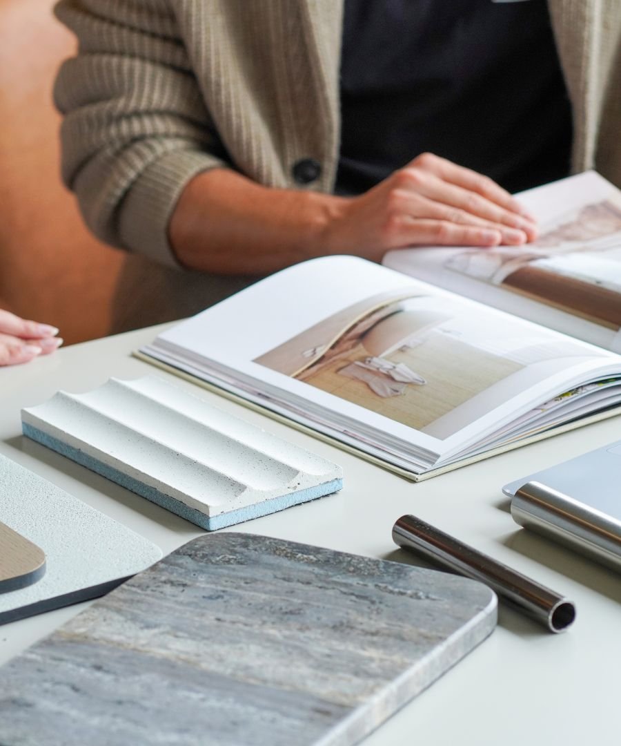 Seleção de amostras de pedras nobres, materiais texturados e catálogo de inspirações numa reunião inicial de interior design, integrando serviços de design de interiores personalizados para casas modernas e casas de luxo.