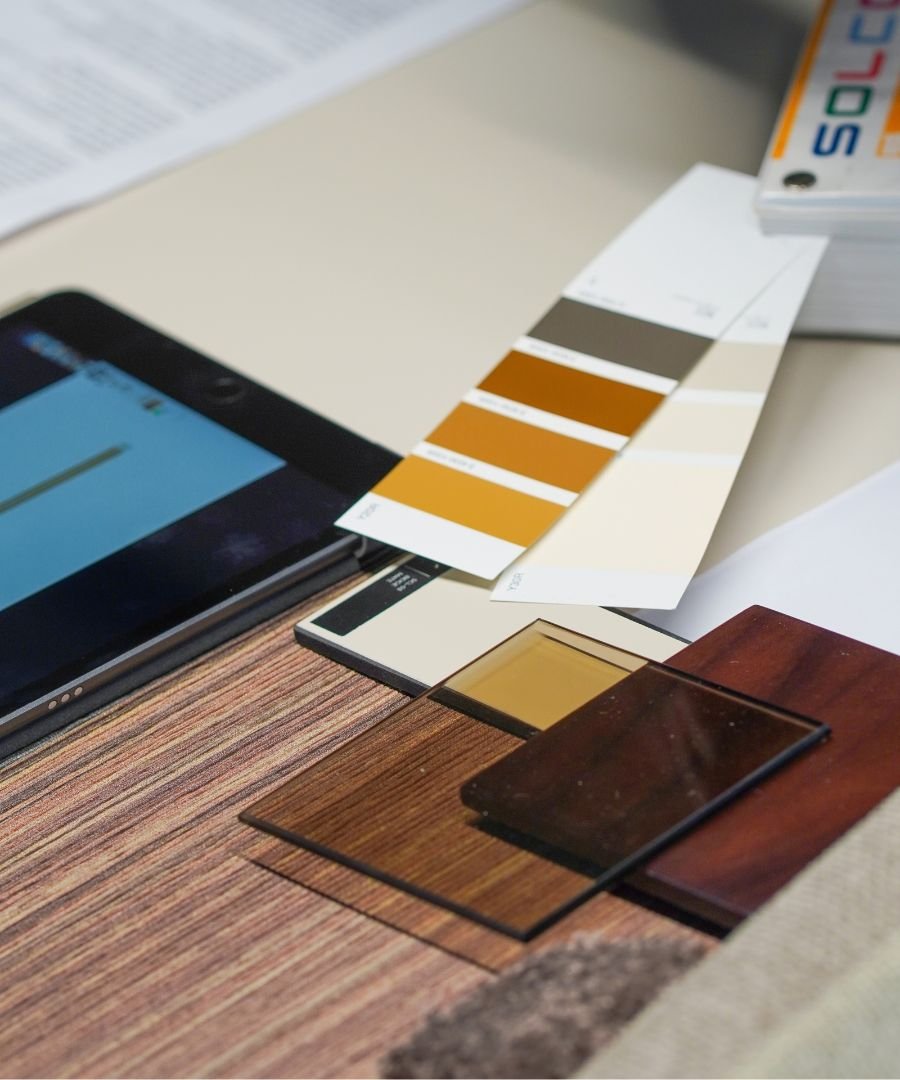 Moodboard com paleta de cores acolhedoras, amostras de madeira, tecidos e vidro sobre a mesa de trabalho, ilustrando os serviços de design de interiores e o conceito de interior design exclusivo para casas modernas e casas de luxo.