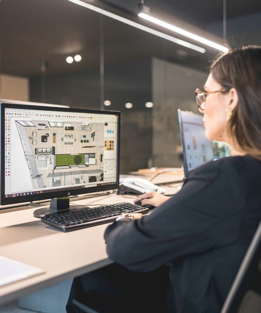 Designer de Interiores a projetar em software 3D o layout de uma habitação contemporânea, demonstrando o rigor técnico dos serviços de design de interiores e do interior design dedicados a casas modernas e casas de luxo.