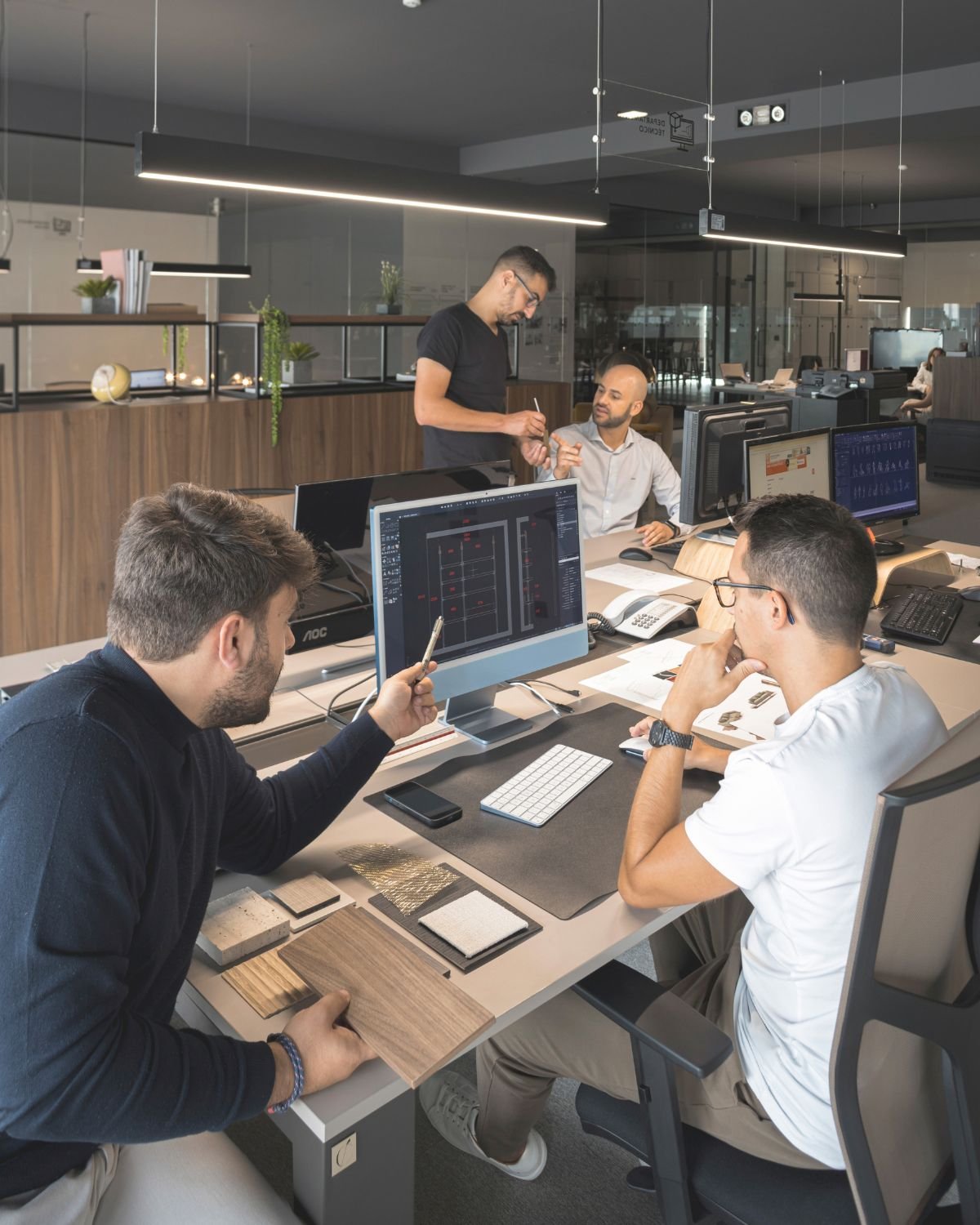 Equipa técnica a planear projetos num escritório que oferece um serviço de design de interiores, criando ideias de decoração para casas de luxo.