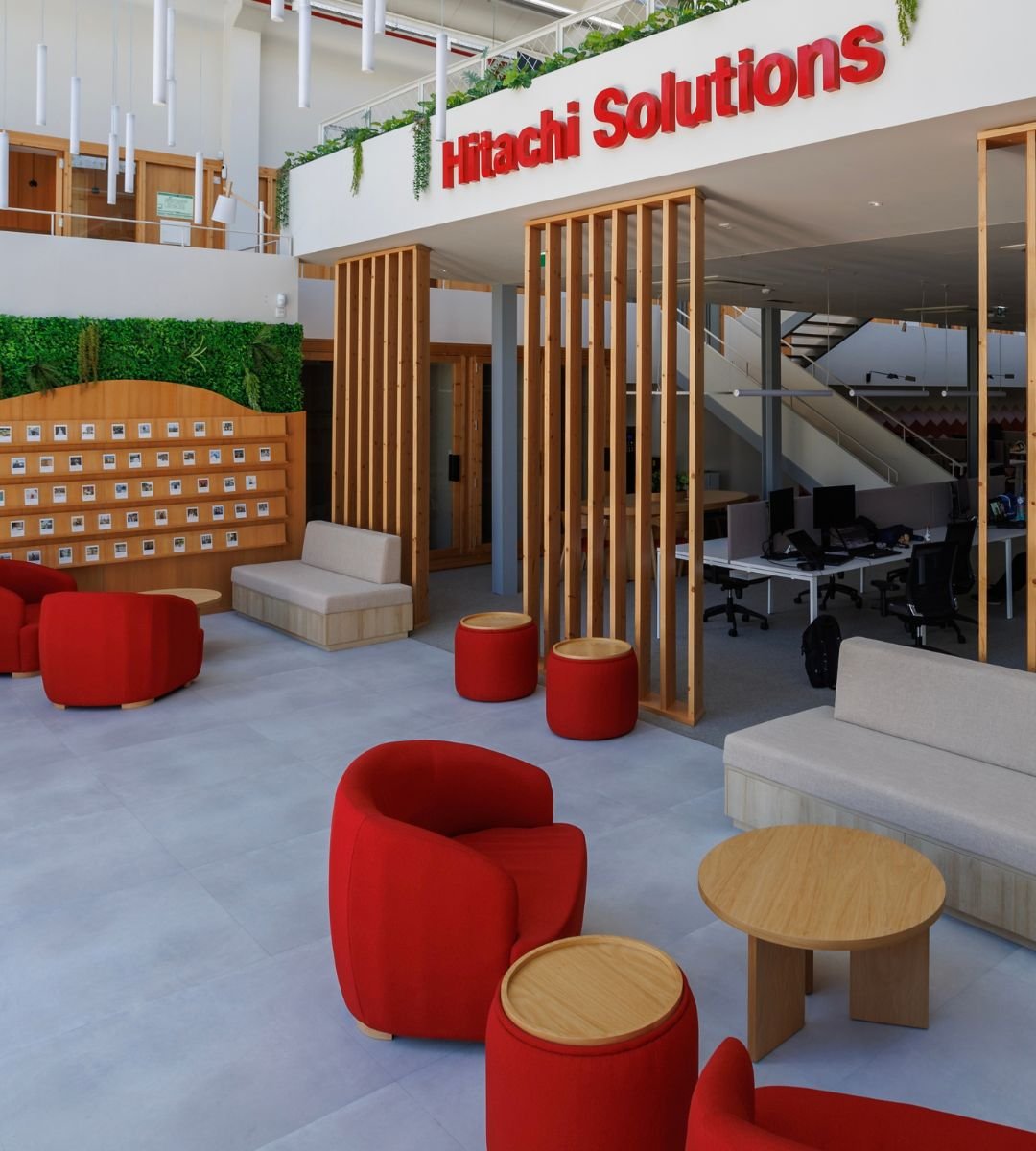 Design de interiores corporativo aplicado a um escritório contemporâneo, integrando áreas de trabalho e zonas de descanso confortáveis com apontamentos em madeira e vegetação.