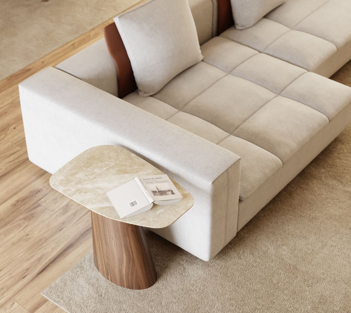 Plano aproximado em ângulo superior focando a extremidade do sofá modular em tecido claro com detalhes em couro no encosto e uma sofisticada mesa de apoio junto ao braço. O tampo em mármore claro com formato orgânico e a base cónica em madeira escura ilustram a versatilidade de exclusivas mesas de apoio numa sala de estar moderna. O livro aberto pousado na superfície transmite uma sensação de tranquilidade e conforto, sugerindo excelentes ideias de decoração para quem aprecia uma criteriosa decoração sala moderna. A textura suave dos estofos em capitoné linear contrasta com a solidez da pedra, evidenciando o cuidado técnico do design de interiores no planeamento de cada detalhe. A presença desta discreta mesa de apoio assegura suporte funcional à leitura, consolidando a elegância exigida numa sala de estar moderna. A harmonia de tons quentes entre a madeira e o piso espelha o conceito refinado da decoração sala moderna, na qual belas mesas de apoio assumem protagonismo sem sobrecarregar a circulação. Esta composição inspira práticas ideias de decoração, demonstrando que o melhor design de interiores prioriza tanto a estética como a ergonomia. Ao posicionar a mesa de apoio junto ao assento, a disposição valoriza a funcionalidade diária de uma requintada sala de estar moderna. A nobreza dos acabamentos reafirma o papel das mesas de apoio na elevação de uma decoração sala moderna, gerando novas ideias de decoração para espaços contemporâneos. A pureza de linhas reforça o prestígio do design de interiores, onde uma escultural mesa de apoio e a qualidade de elegantes mesas de apoio enriquecem a decoração sala moderna, definindo uma acolhedora sala de estar moderna pautada por memoráveis ideias de decoração, excelente decoração sala moderna e a precisão estética de um intemporal design de interiores que eleva esta sala de estar moderna com inspiradoras ideias de decoração e o melhor do design de interiores.