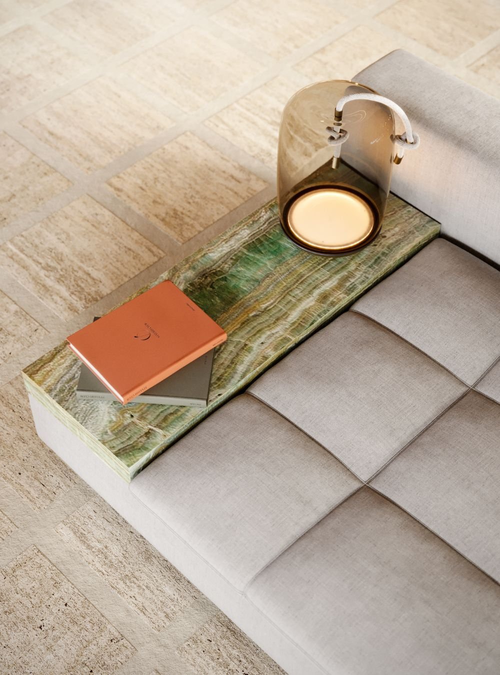 Detalhe do sofá com mesa de apoio em pedra e iluminação decorativa, integrado no design de interiores da sala de estar.