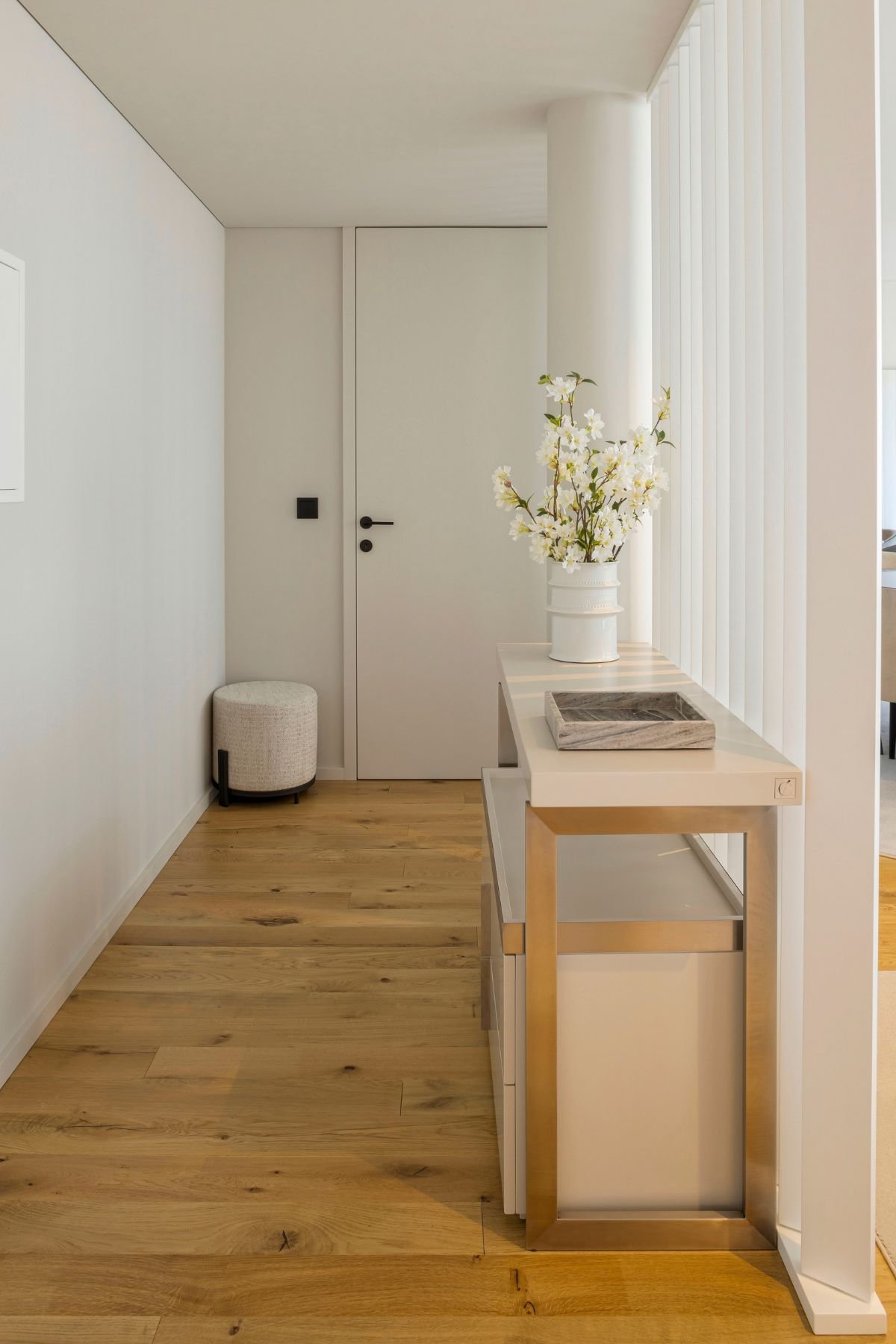 Corredor elegante com chão em madeira e móvel de apoio claro com detalhes metálicos, ideal para hall de entrada decoração com aparador hall de entrada e consolas de entrada num hall de entrada pequeno.