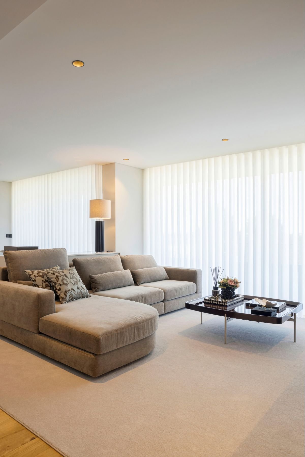 Vista aproximada de um acolhedor sofa chaise longue com almofadas e mesa de centro elegante, valorizando a decoração sala nesta luminosa sala de estar em open space.