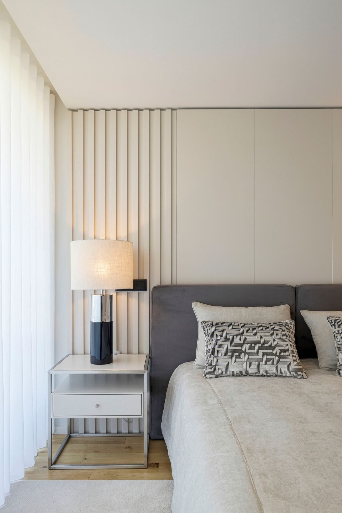 Mesa de cabeceira moderna com candeeiro elegante em quarto de casal decorado com painel ripado, unindo interior design e decoração de quarto em casas modernas.