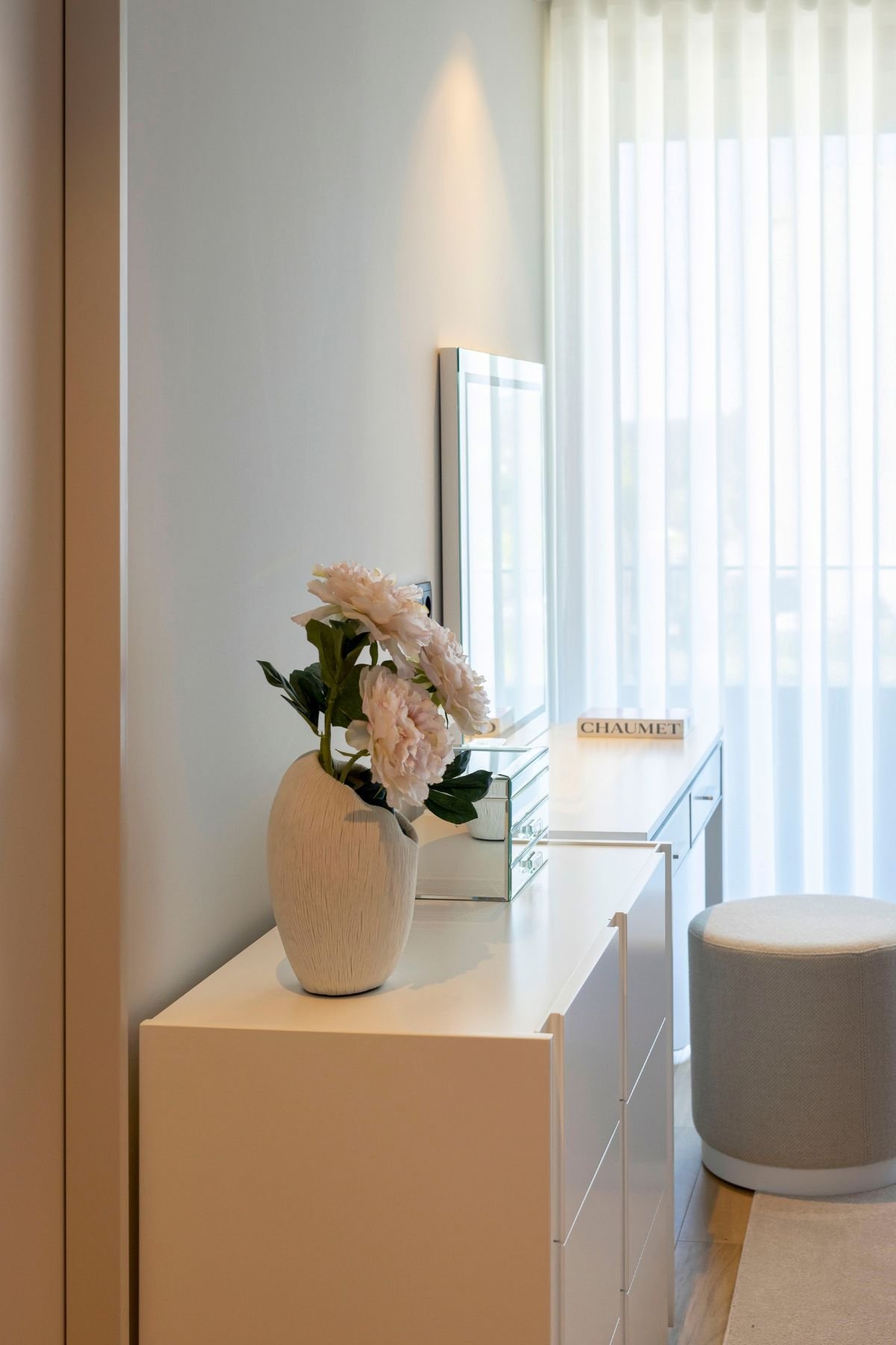 Jarra de flores sobre cómoda em frente ao toucador com espelho num walking closet acolhedor, integrando módulos de closet aberto para criar um dream closet único.