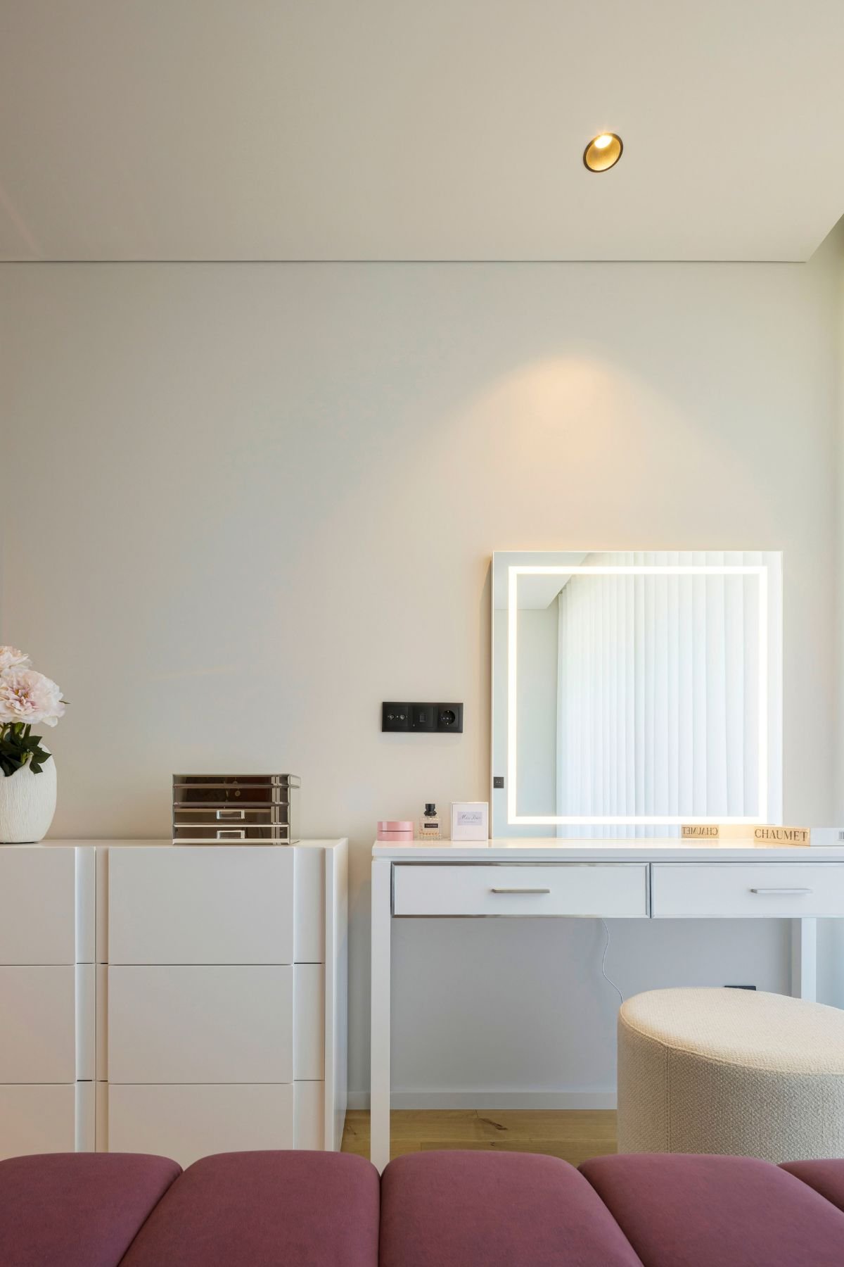 Zona de toucador com espelho iluminado e gaveteiro branco num walking closet requintado, pensado para conjugar com closet aberto num dream closet contemporâneo.