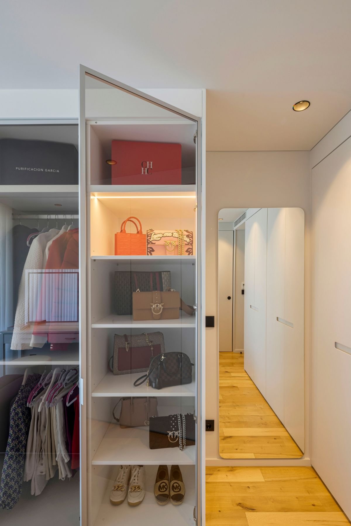 Prateleiras organizadas de malas e sapatos num closet aberto integrado num walking closet funcional com toucador com espelho, ideal para um dream closet de luxo.