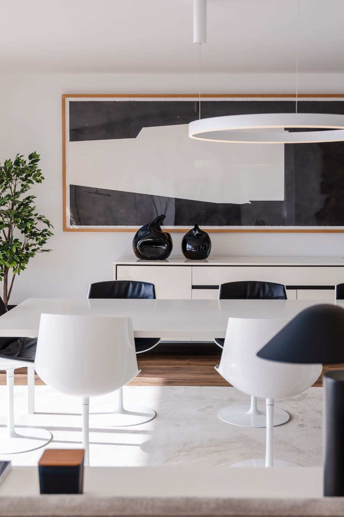 Detalhe das cadeiras de jantar de design nórdico e da consola branca de apoio com peças decorativas.
