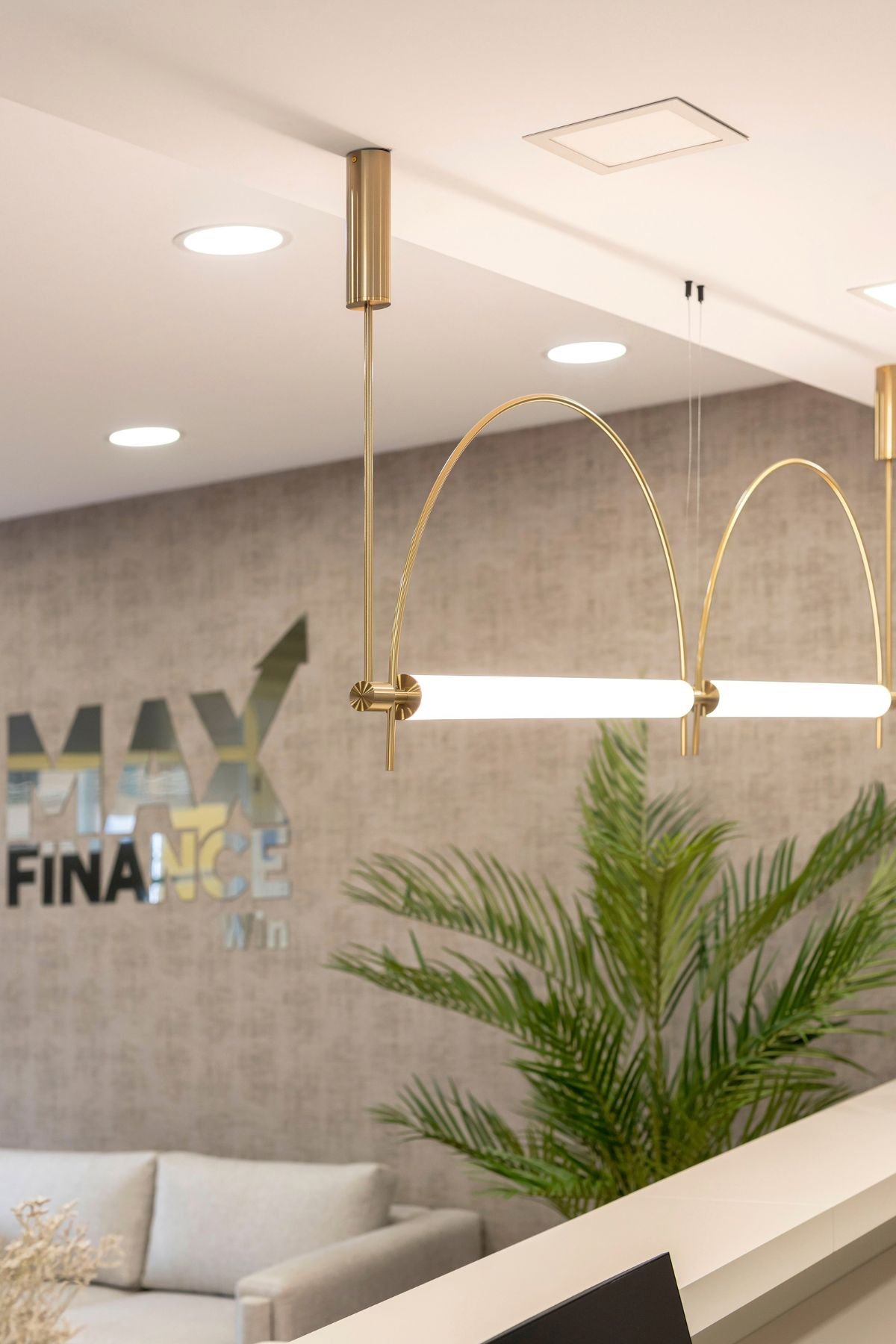 Pormenor do candeeiro de teto em metal dourado com acabamento contemporâneo, em destaque no hall de entrada da Max Finance Win.