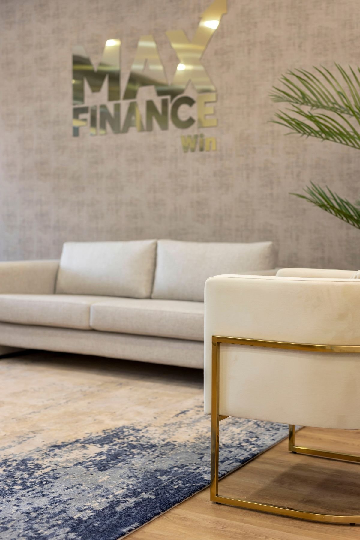 Detalhe da estrutura em aço inoxidável dourado e veludo da cadeira, sobre o tapete com tons azul-marinho no projeto Max Finance Win.