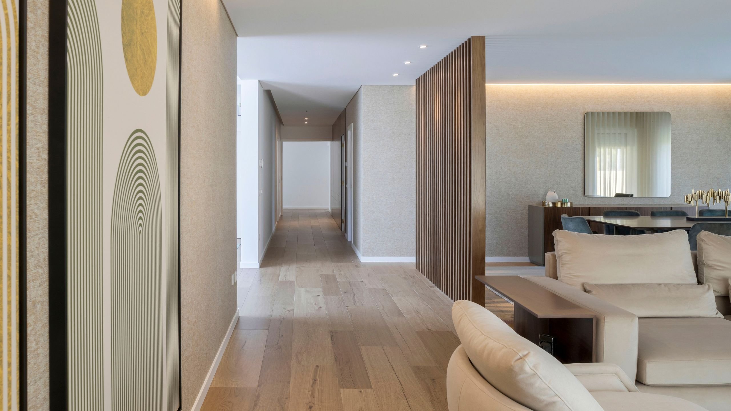 Corredor de circulação delimitado por ripado de madeira que separa a zona de estar da sala de jantar contemporânea.