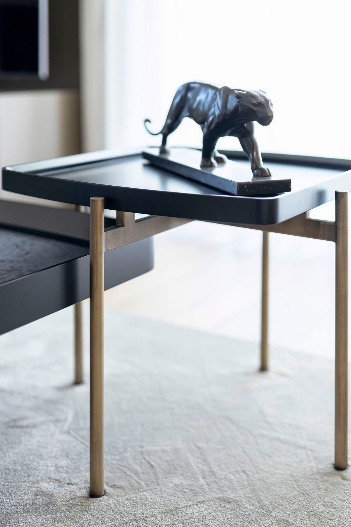 Detalhe da mesa de apoio com estrutura metálica e escultura decorativa de uma pantera no tampo.