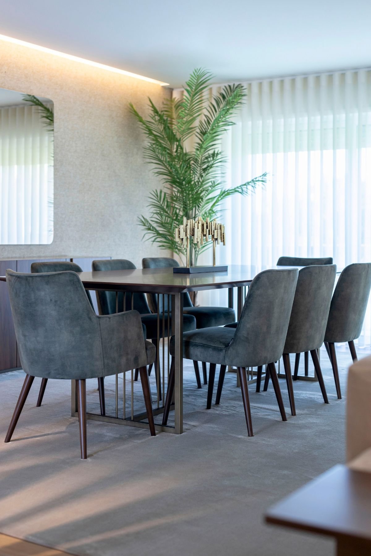 Perspetiva aproximada da mesa de jantar destacando a peça decorativa central e os pés em nogueira das cadeiras.