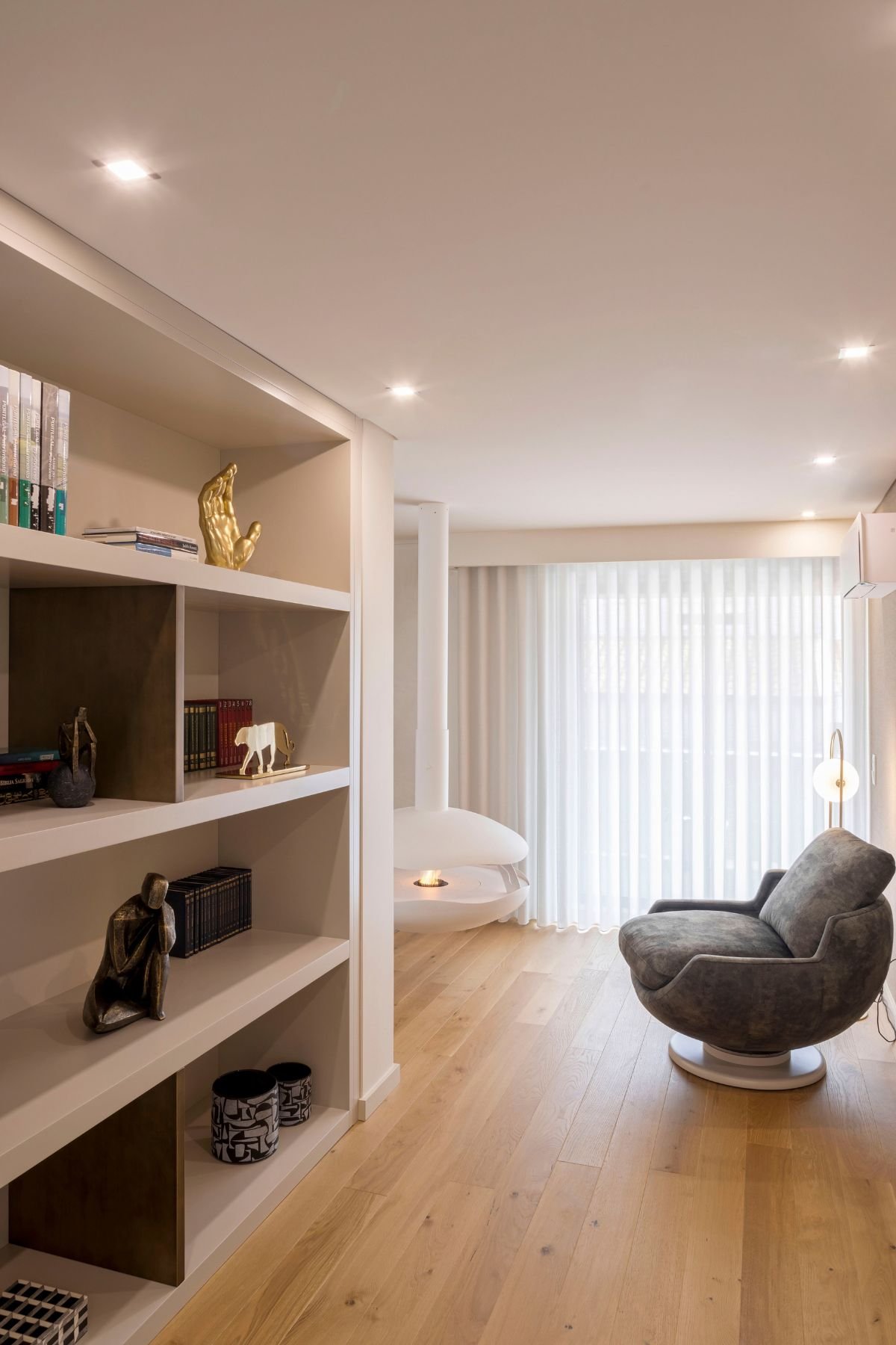 Recanto de leitura com poltrona giratória em pele e lareira suspensa em open space luminoso, revelando o melhor do interior design e decoração em casas de luxo.