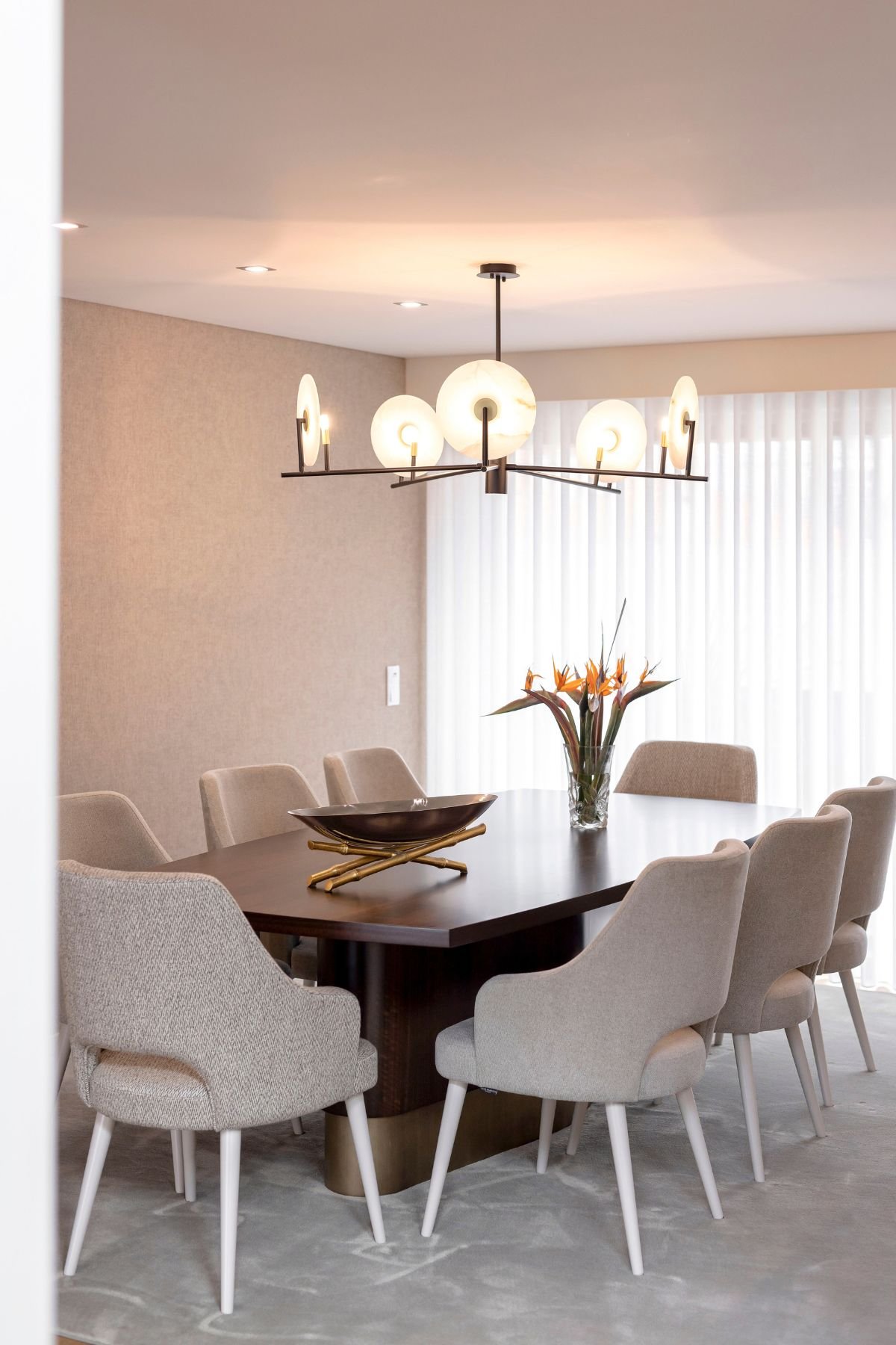 Luminária suspensa escultural sobre mesa para sala de jantar e conjunto de cadeira de sala de jantar, definindo o interior design da sala de jantar.