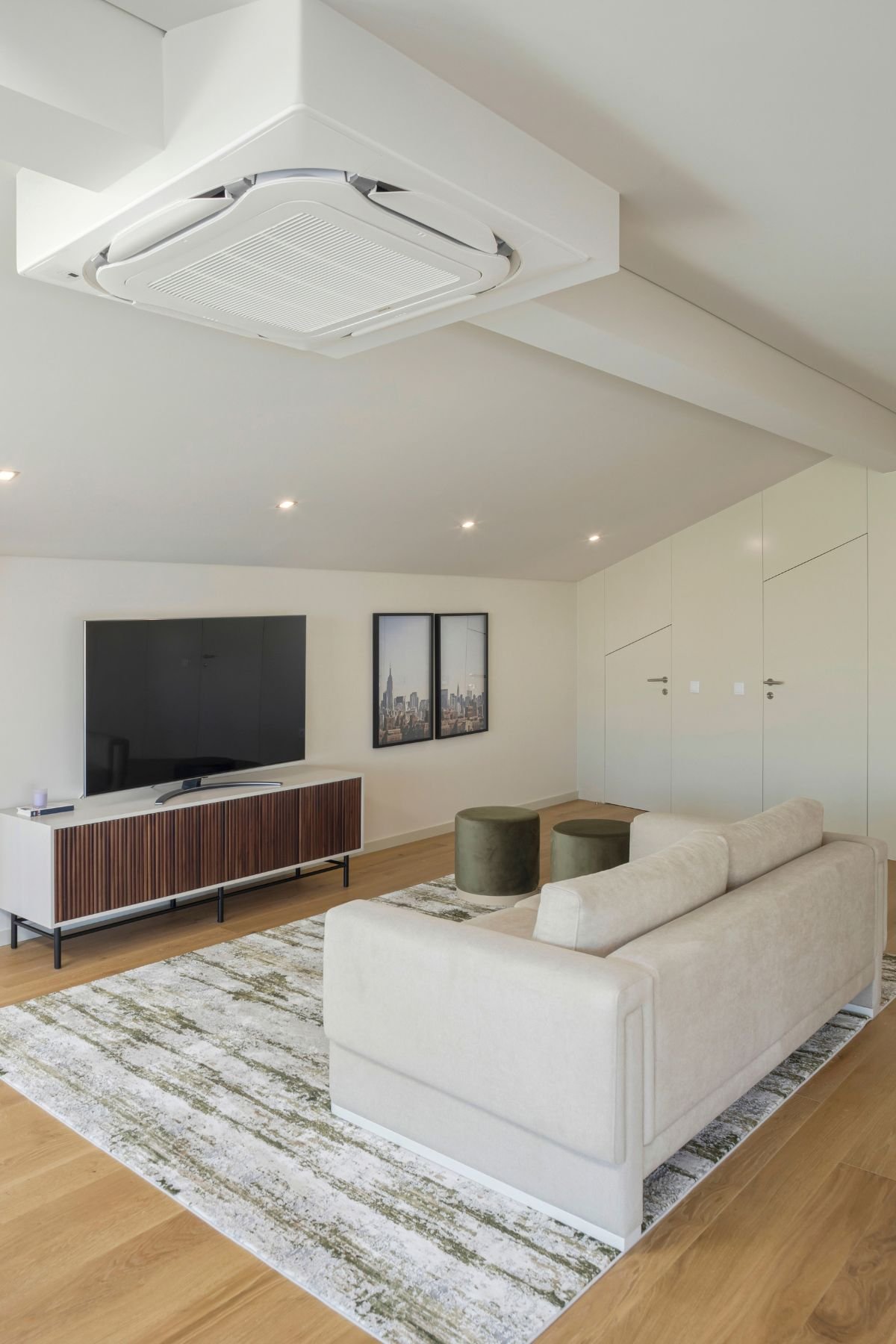 Zona de lazer em open space com sofá claro e móvel de TV ripado, exemplo de salas de estar modernas com interior design e decoração sofisticados.