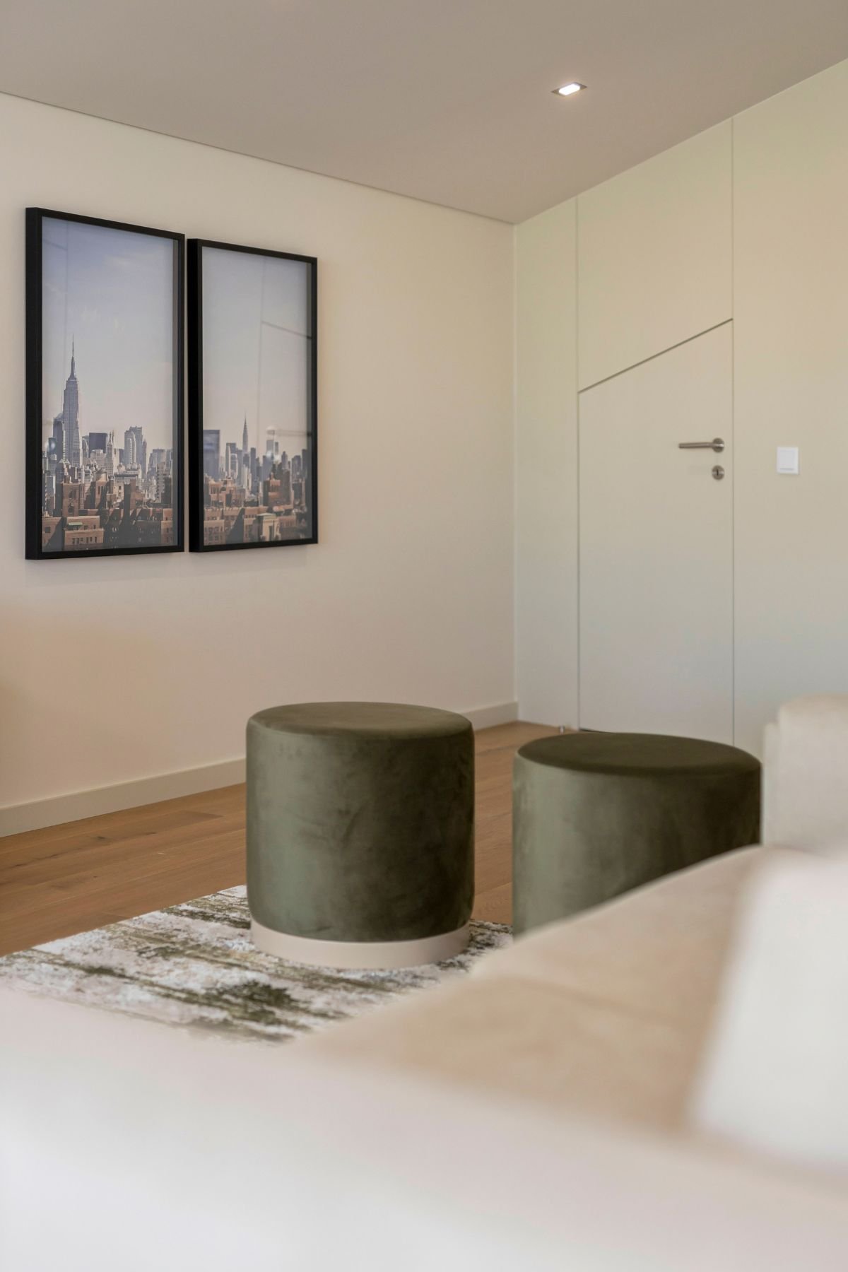 Puffs em veludo verde junto a quadros urbanos em open space elegante, refletindo o requinte de interior design e decoração para salas de estar modernas.