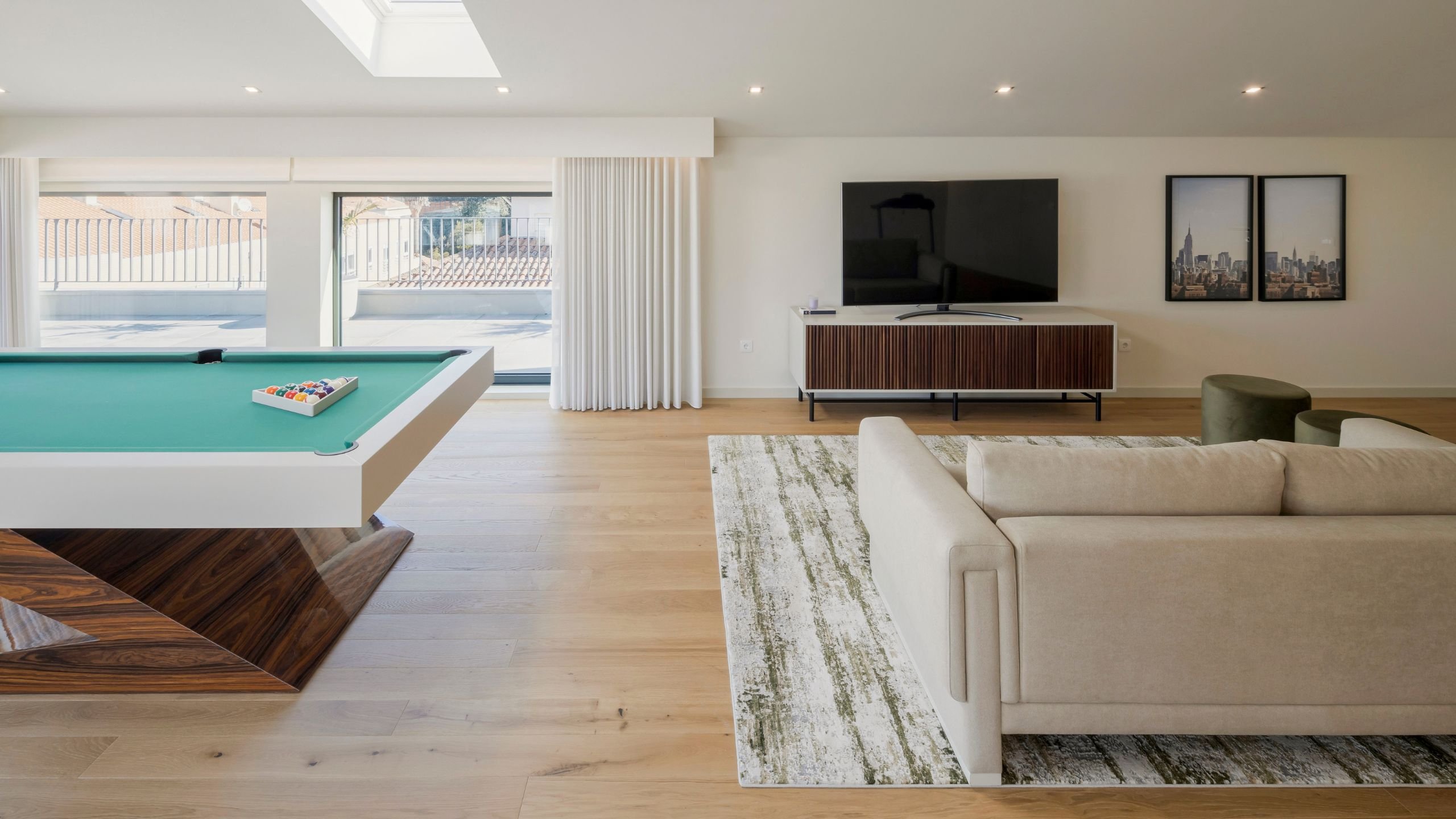 Vista panorâmica de open space com mesa de bilhar e lounge de TV, aliando o conceito de salas de estar modernas a um excecional interior design e decoração.