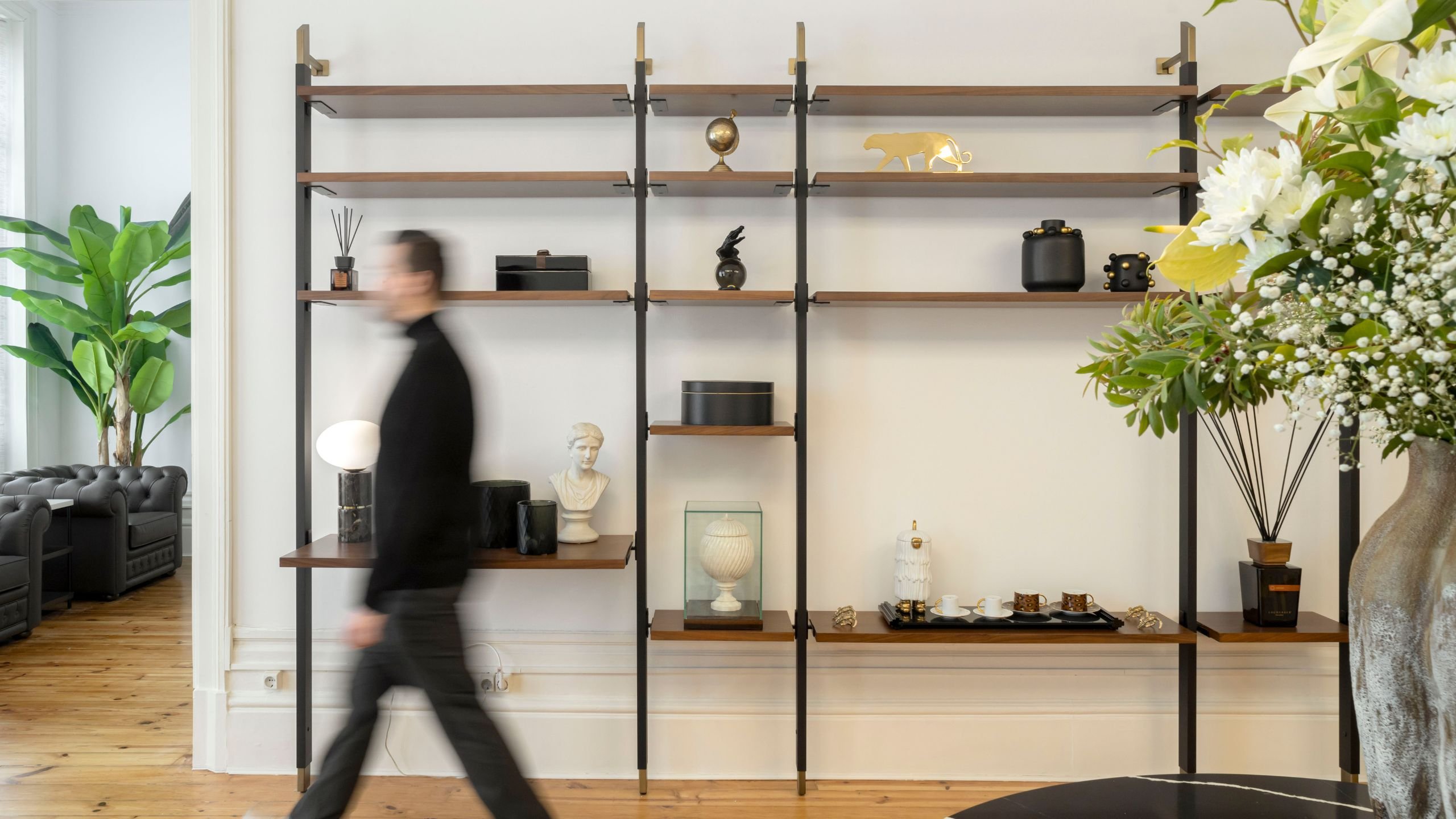 Estante metálica de parede decorada com objetos minimalistas e vasos decorativos, integrada na decoração e mobiliário de escritório.