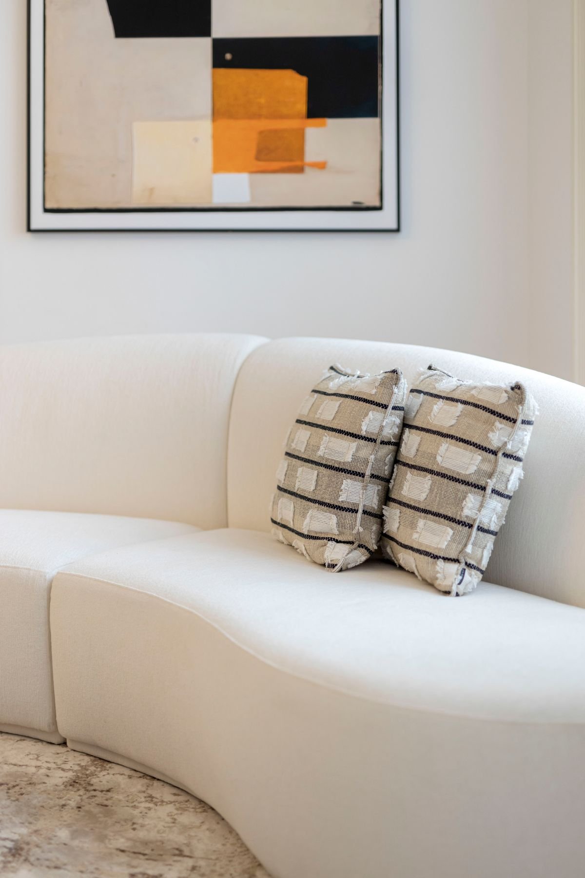 Pormenor de almofadas decorativas com textura sobre sofá branco de linhas curvas, ideal para um toque de conforto no design de interiores.