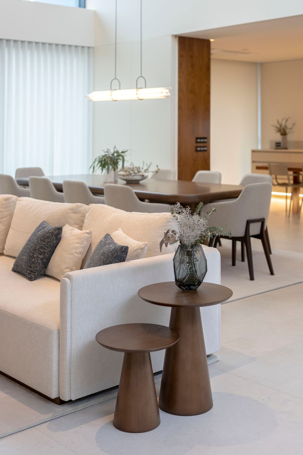 Mesas de apoio em madeira junto ao sofá claro com almofadas decorativas na sala de estar moderna.