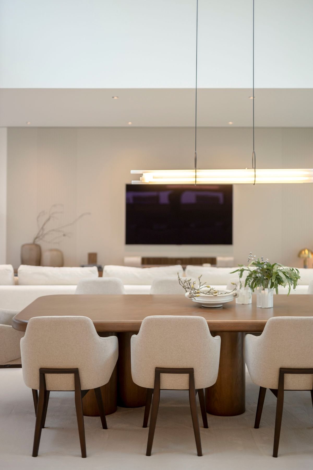 Pormenor da mesa de jantar em madeira escura com centro de mesa decorativo e cadeiras de jantar elegantes.