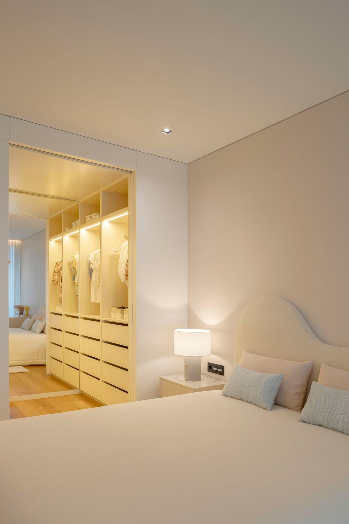 Vista em perspetiva da cama de casal com cabeceira de cama curva e candeeiro de mesa no quarto juvenil.