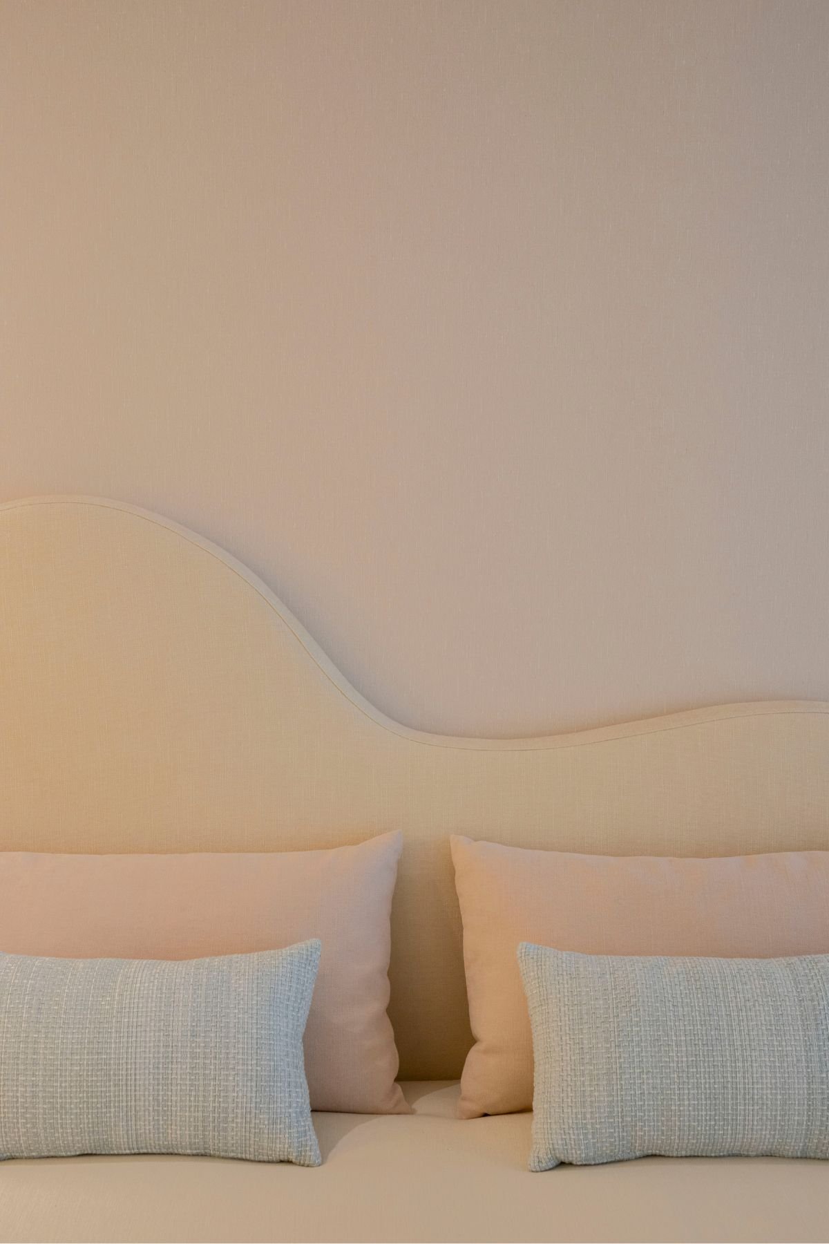 Pormenor dos têxteis de cama no quarto juvenil destacando almofadas decorativas em tons rosa e azul pastel.
