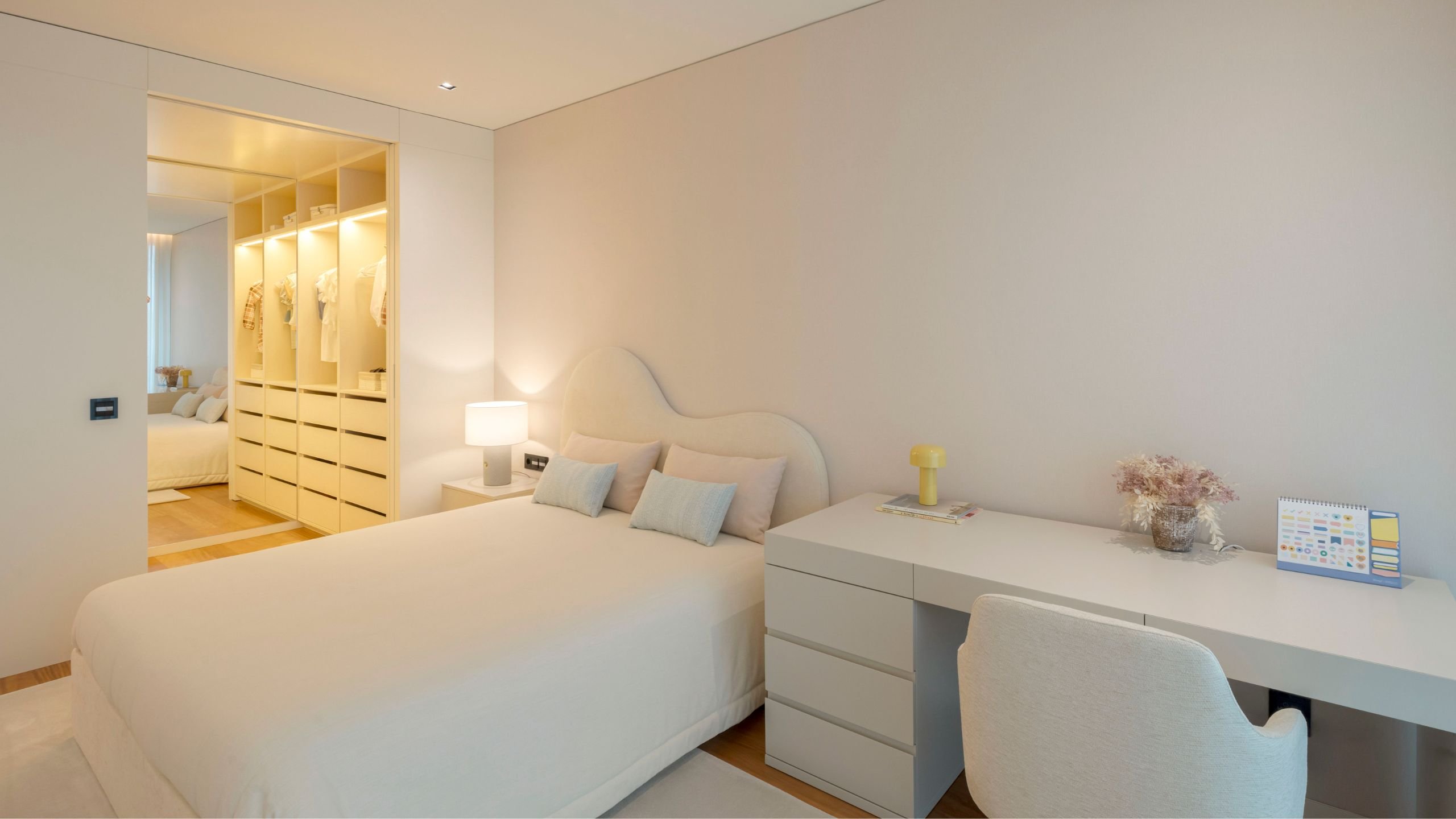 Vista geral do quarto juvenil com cama de casal, cabeceira de cama orgânica e secretária com cadeira de escritório.