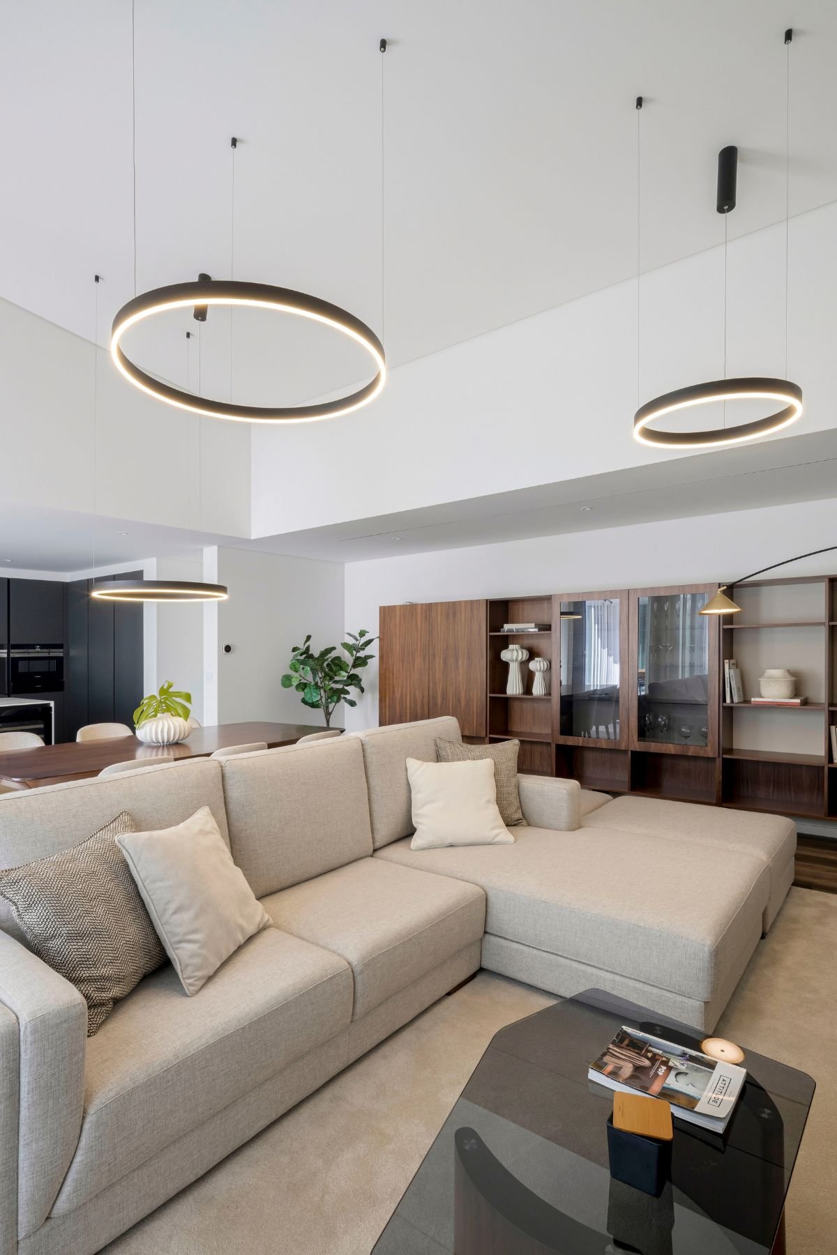 Perspetiva angular da sala de estar destacando o sofá modular bege e a mesa de centro com tampo escuro e pés em nogueira.