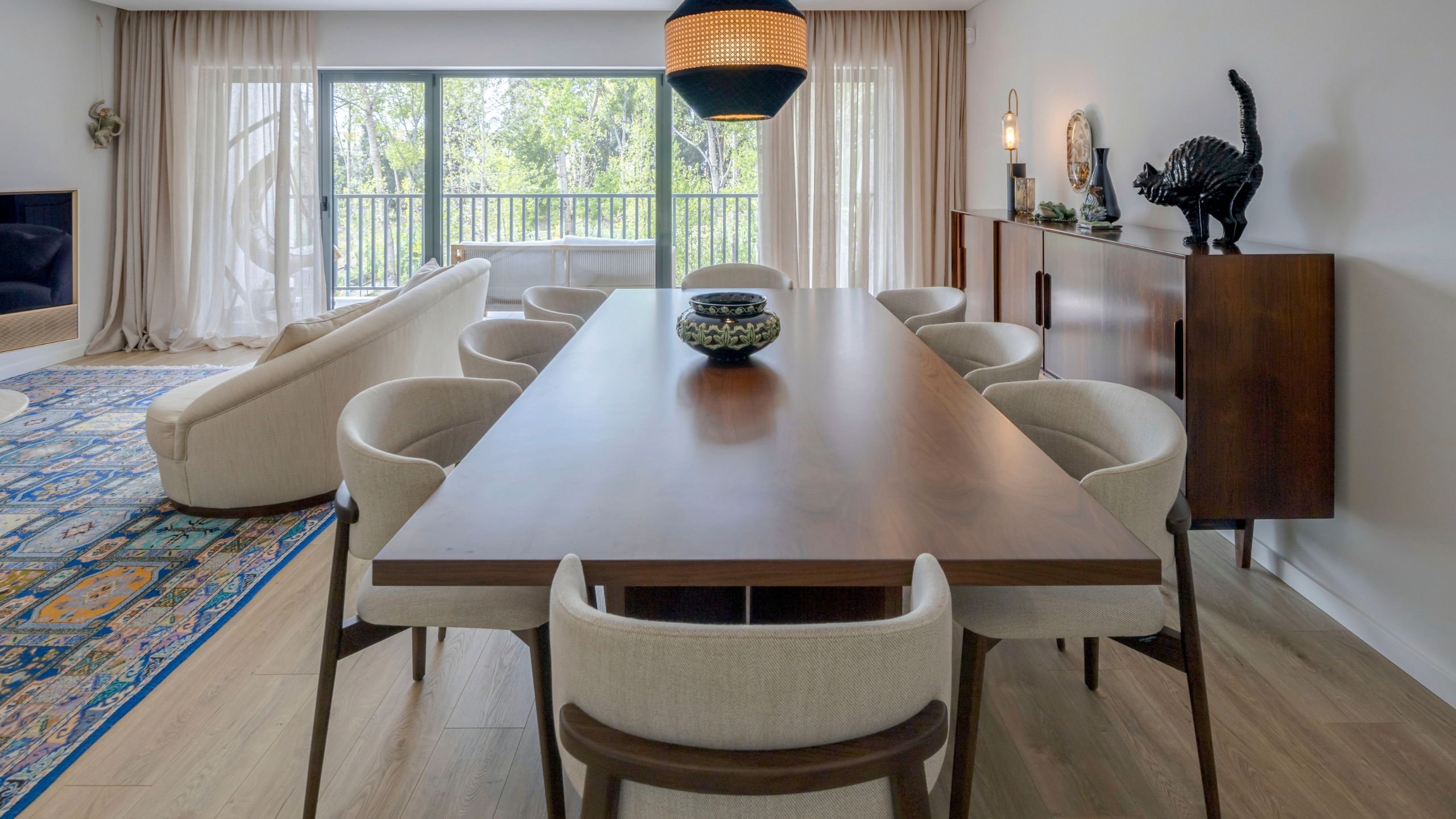 Perspetiva longitudinal da mesa de jantar sala, acompanhada por cada cadeira sala de jantar Coffee estofada, sob iluminação suspensa de design de interiores.