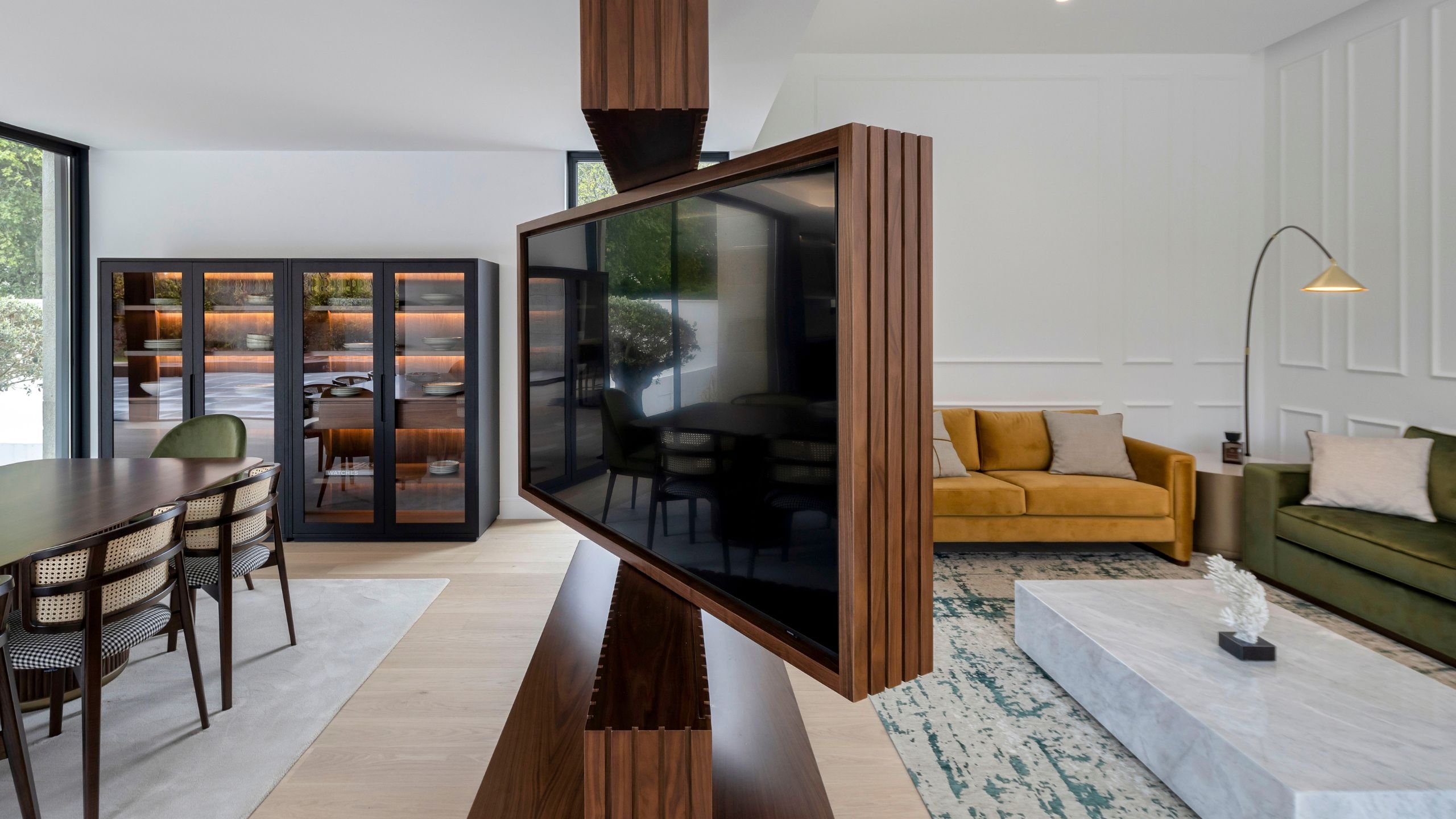 Painel ripado giratório integrado, como exemplo de moveis sala tv modernos entre a zona de jantar e a sala de estar moderna com sofá, poltrona para sala e mesa de centro.