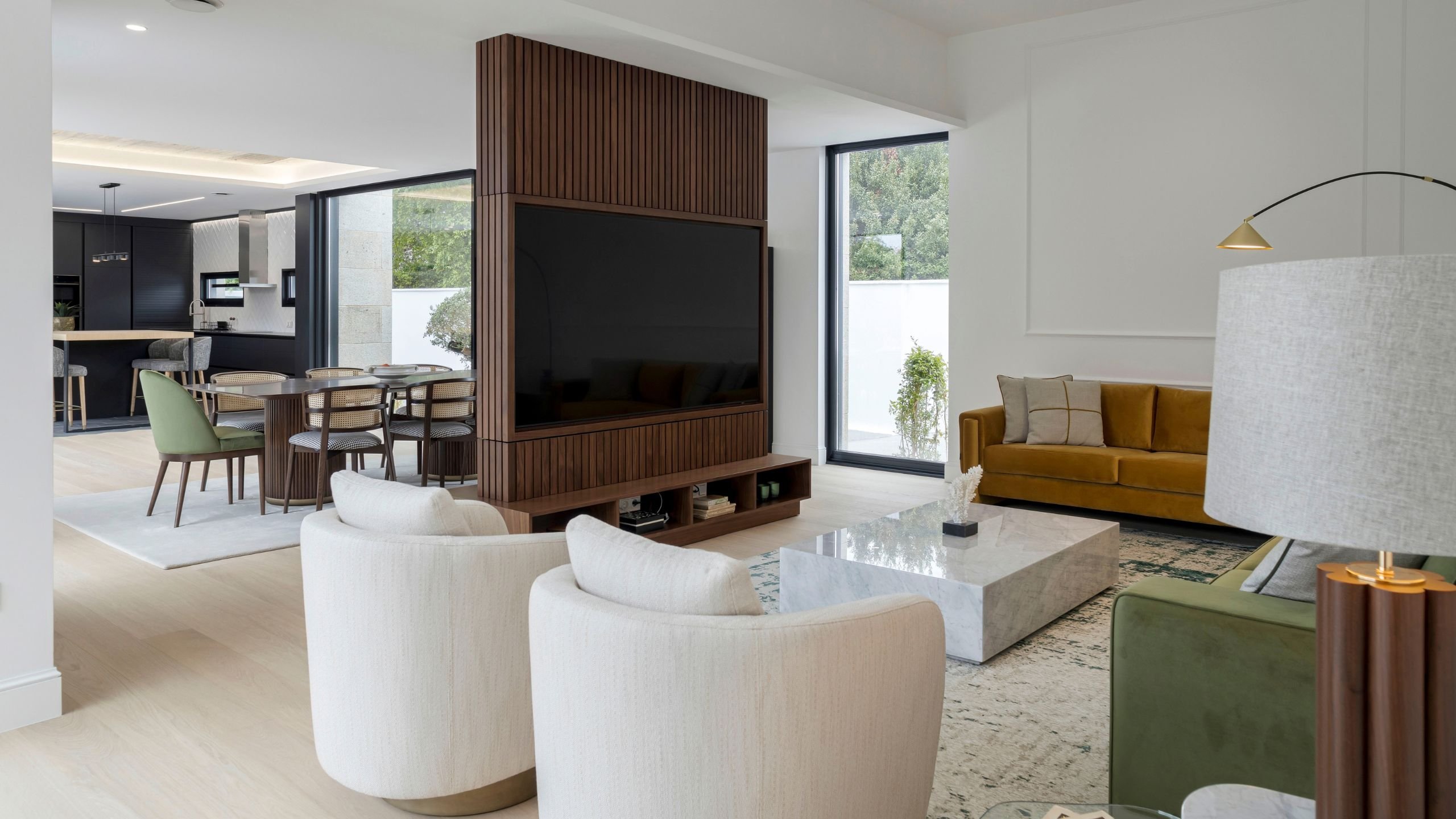 Vista de sala de estar moderna com moveis sala tv modernos em nogueira, dupla poltrona para sala giratória e confortável sofá sob iluminação acolhedora.