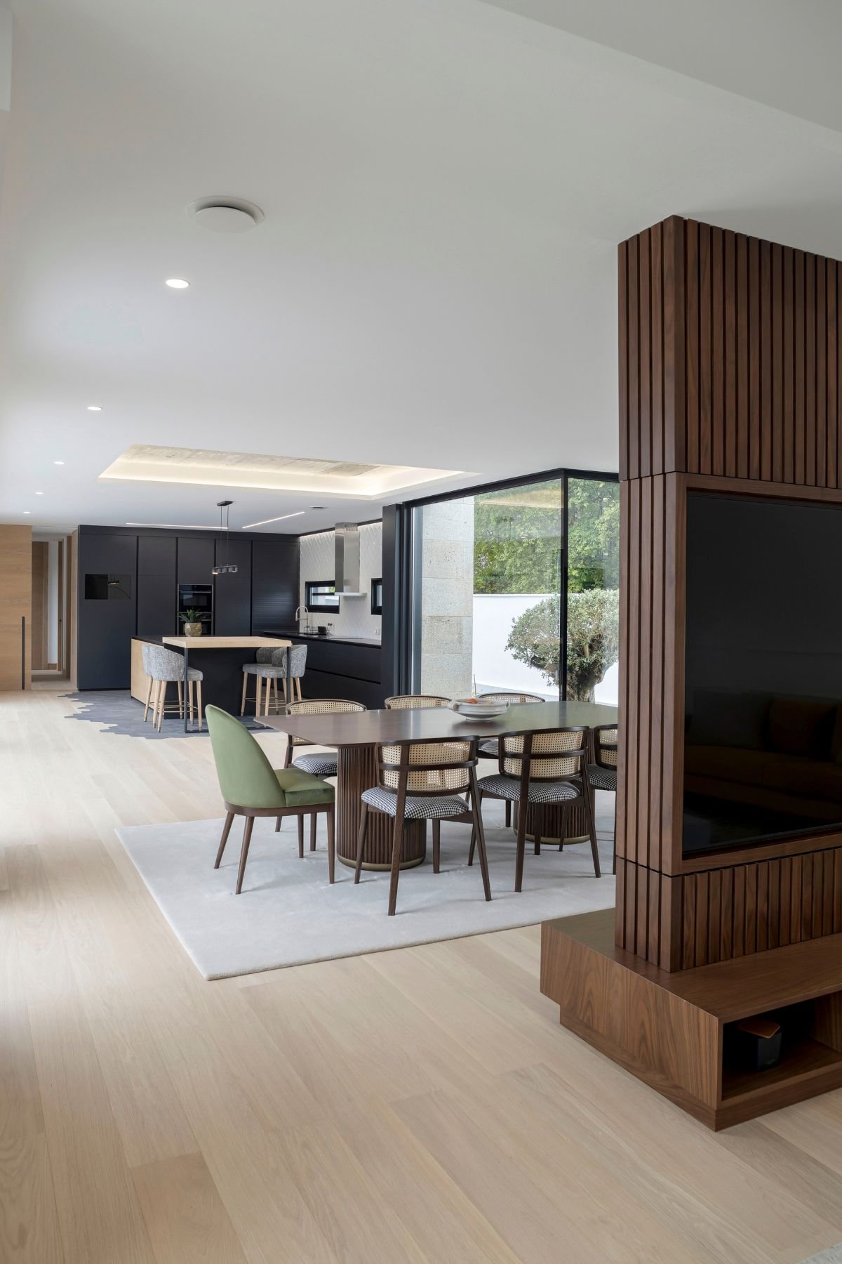 Perspetiva de sala de jantar em open space com ampla mesa para sala de jantar, cadeira sala de jantar com apontamentos verdes e ligação à cozinha contemporânea.