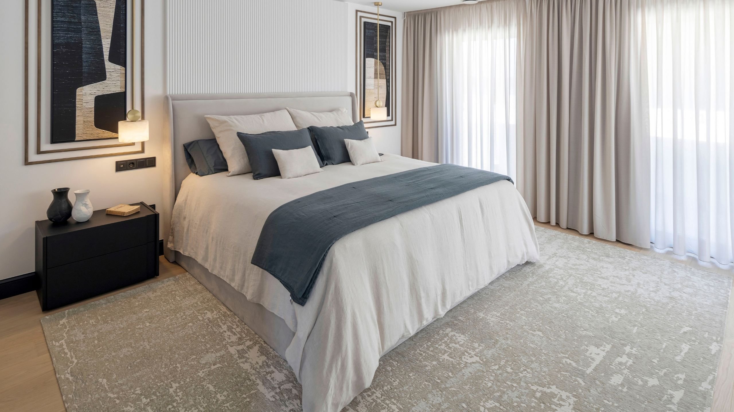 Cama de casal acolhedora acompanhada por mesa de cabeceira escura e cortinas fluidas na decoração de quarto.