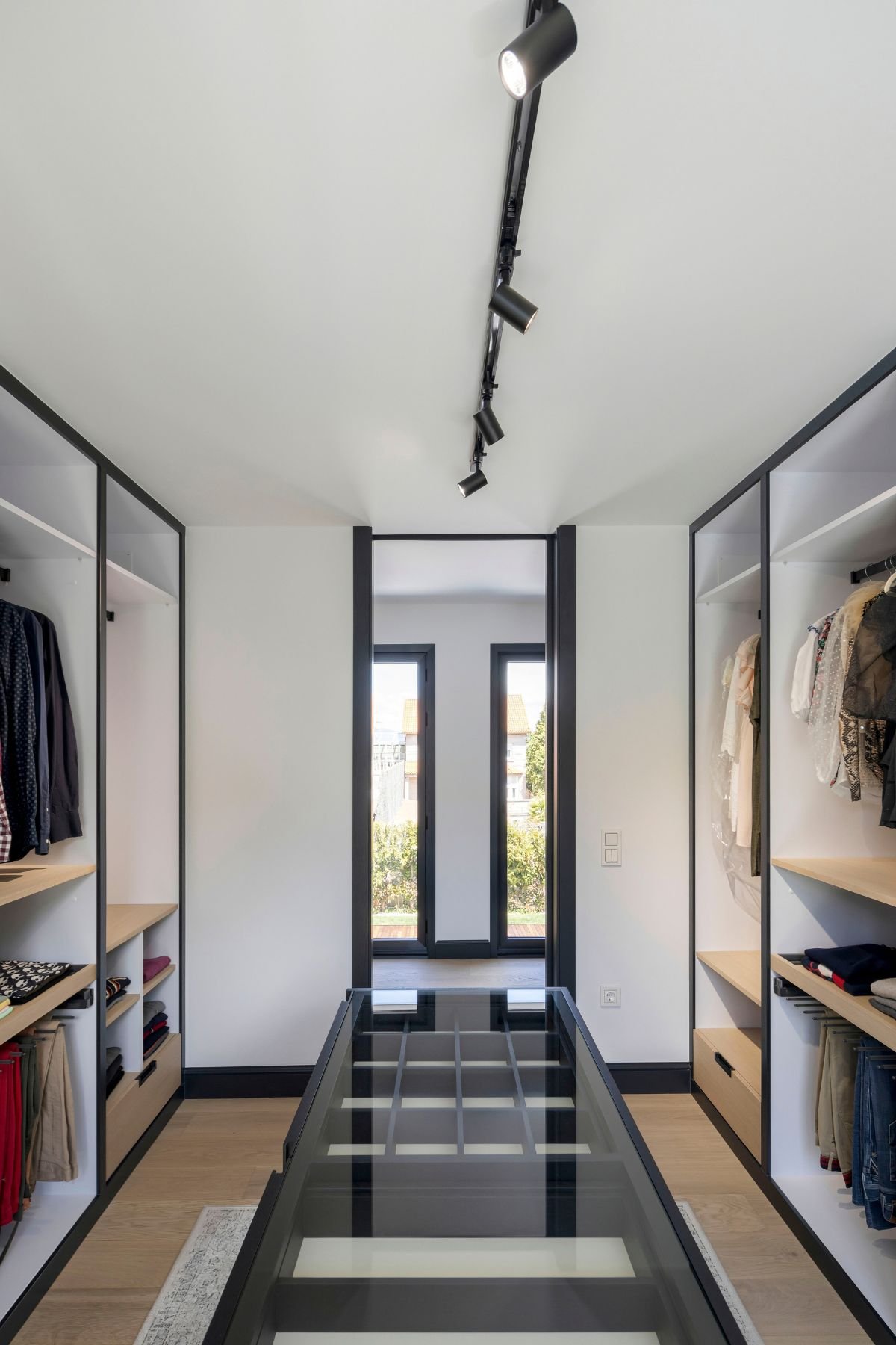 Perspetiva linear de dream closet com iluminação em calha técnica e closet aberto, aliando arrumação de walk-in closet a um moderno design de interiores.