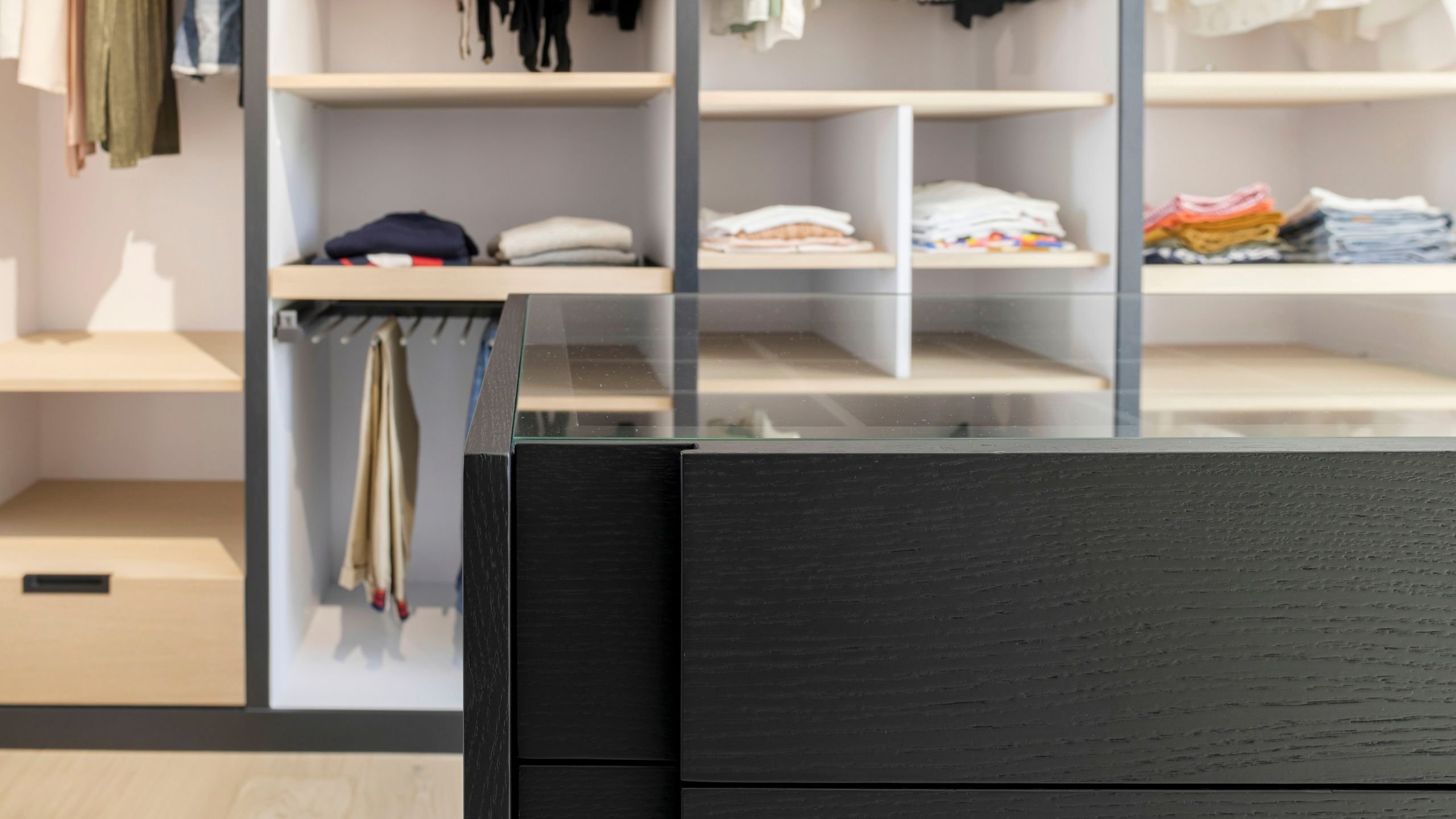 Pormenor de ilha com tampo de vidro e prateleiras de um closet aberto, espelhando o cuidado de design de interiores num dream closet walk-in closet funcional.