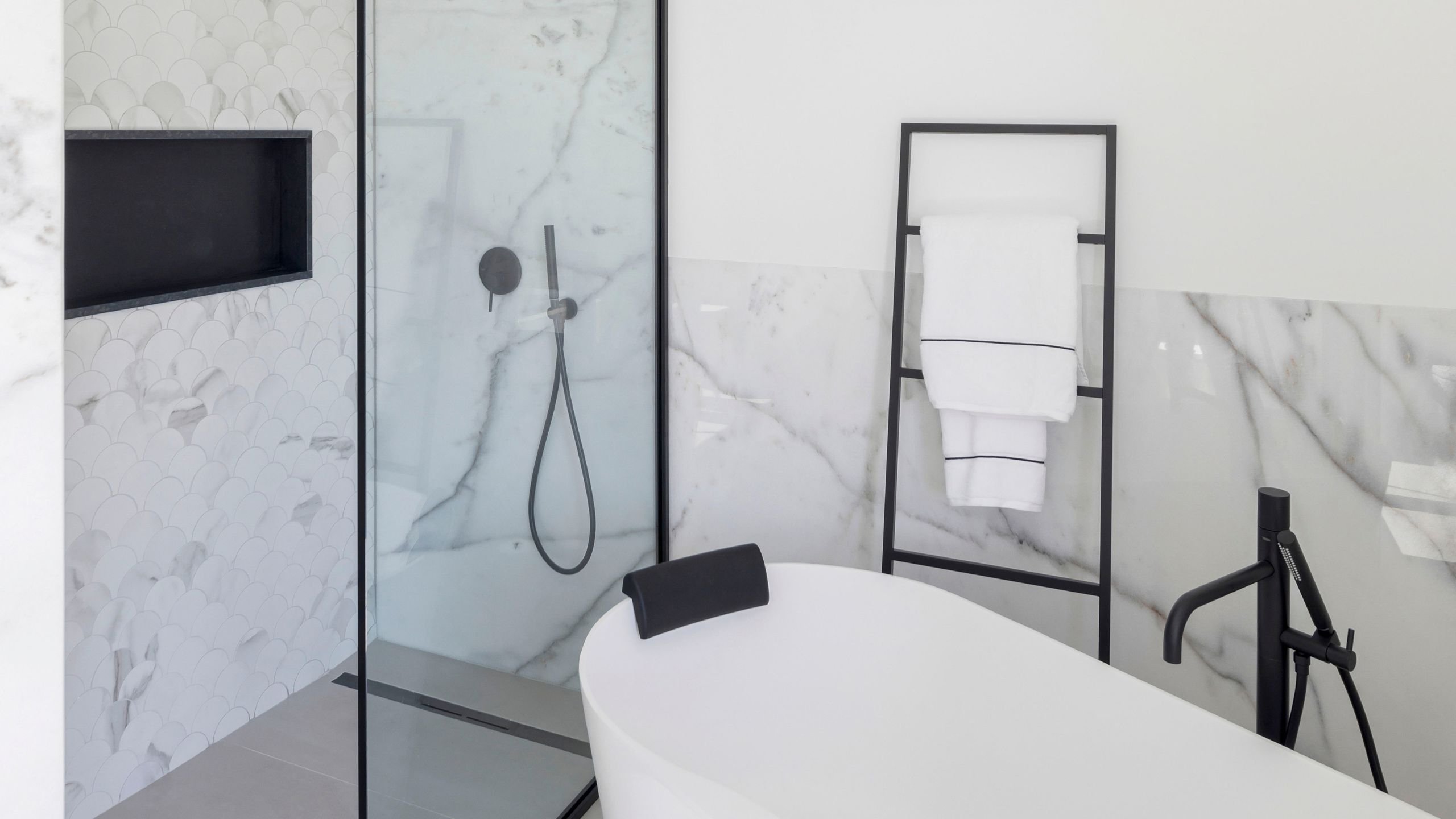Banheira freestanding e duche com revestimento marmoreado, combinando na perfeição com o armário casa de banho, o requinte de interior design e casas de banho modernas.