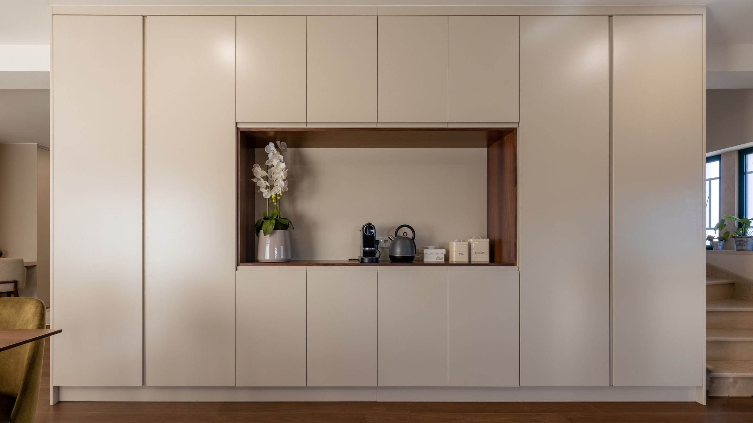 Enquadramento frontal dos móveis de cozinha planeados com nicho central decorado.