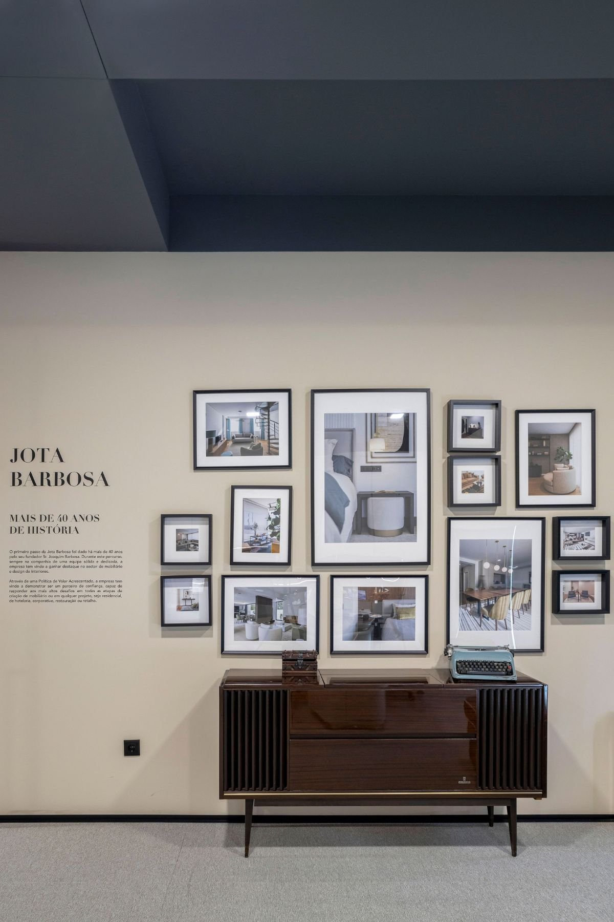 Móvel aparador em madeira com máquina de escrever antiga sob parede de quadros decorativos de projeto de interiores.