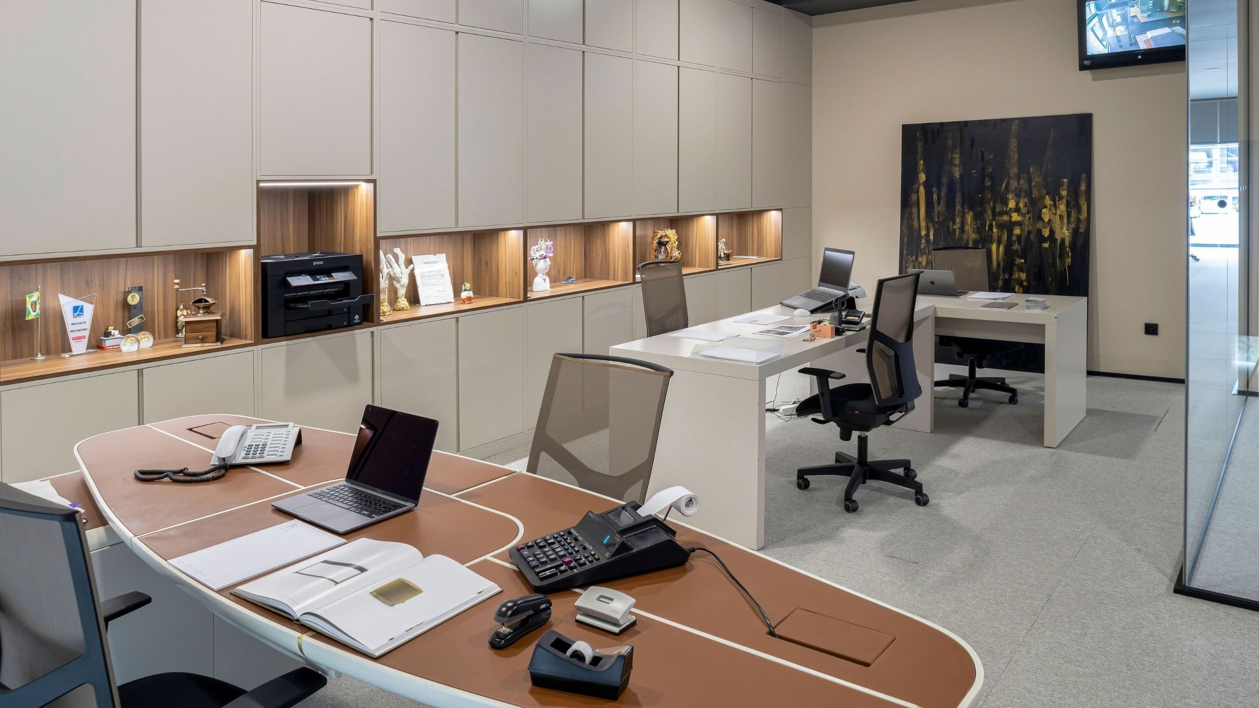 Panorâmica do gabinete de administração equipado com secretária com arrumação, bancadas executivas e cadeira de escritório.