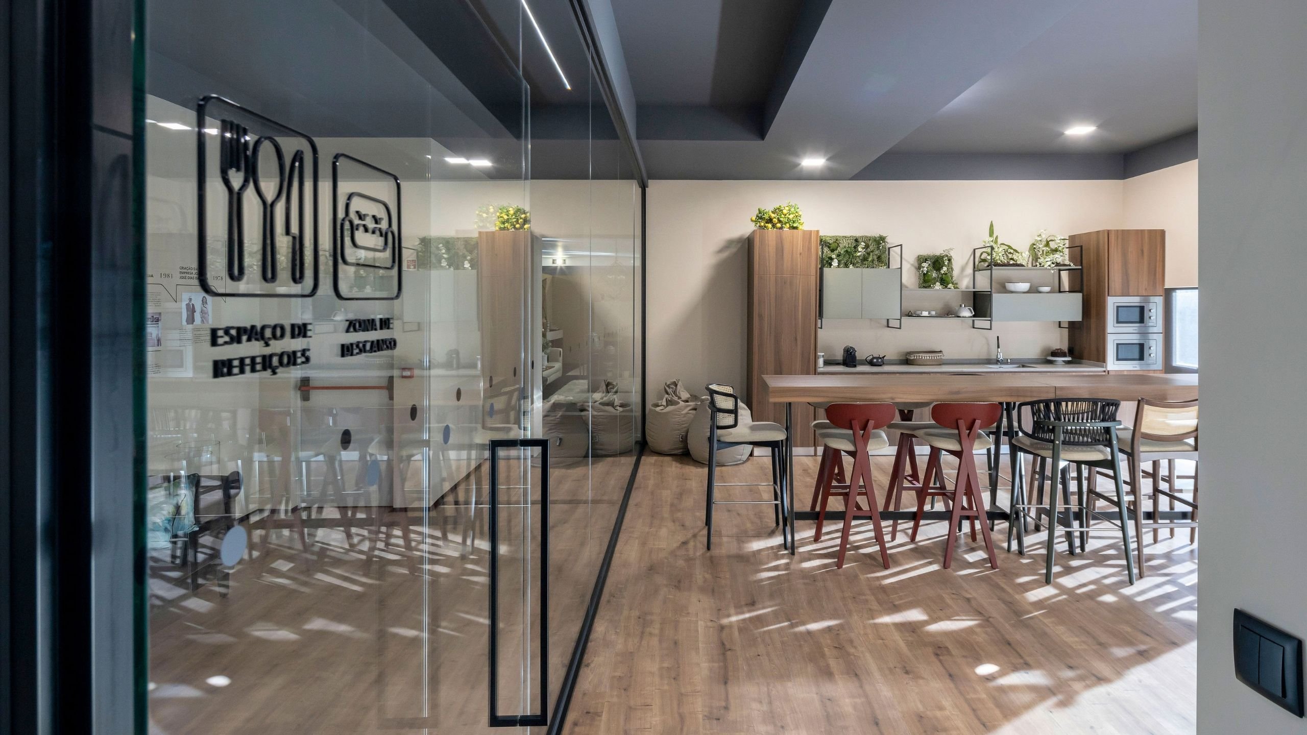Entrada envidraçada para o Espaço de Refeições e Zona de Descanso com bancada em madeira e banco de bar no projeto de interiores.