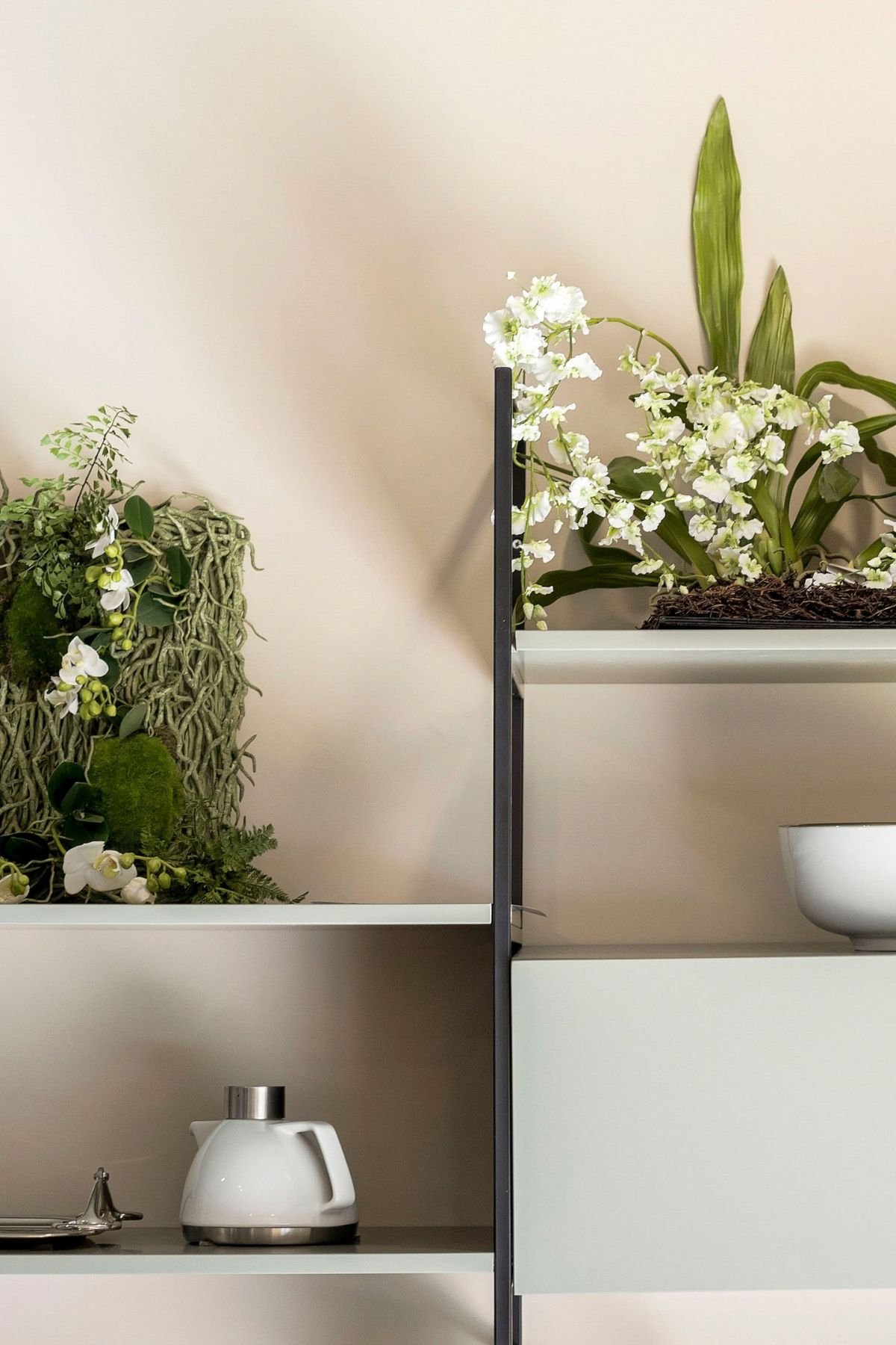 Pormenor decorativo de prateleira metálica com arranjos florais integrados no design de interiores e projeto de interiores.