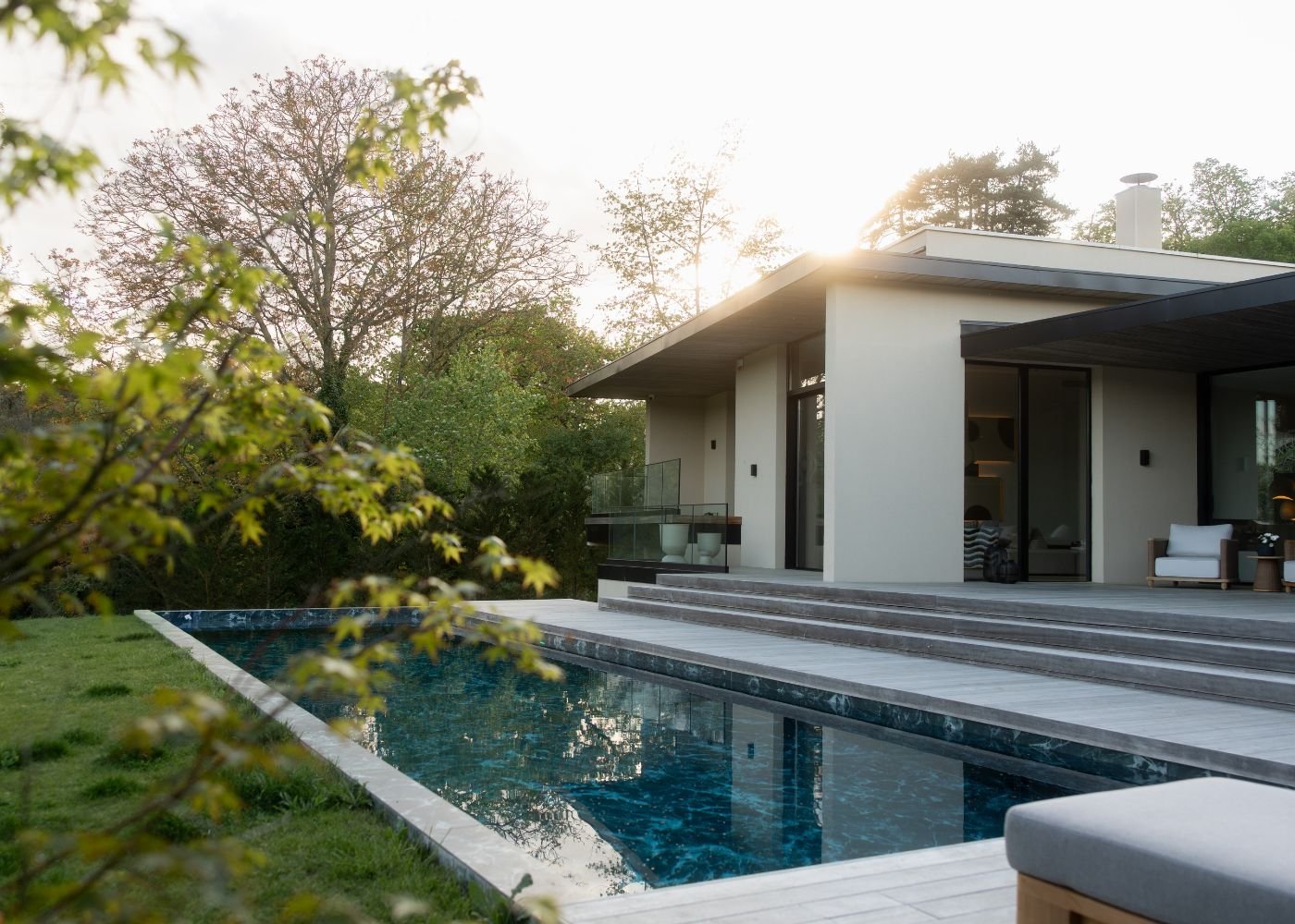 Piscina e fachada de uma das nossas moradias de luxo, que integram os serviços de design de interiores, interior design e a decoração de áreas exteriores ao entardecer.