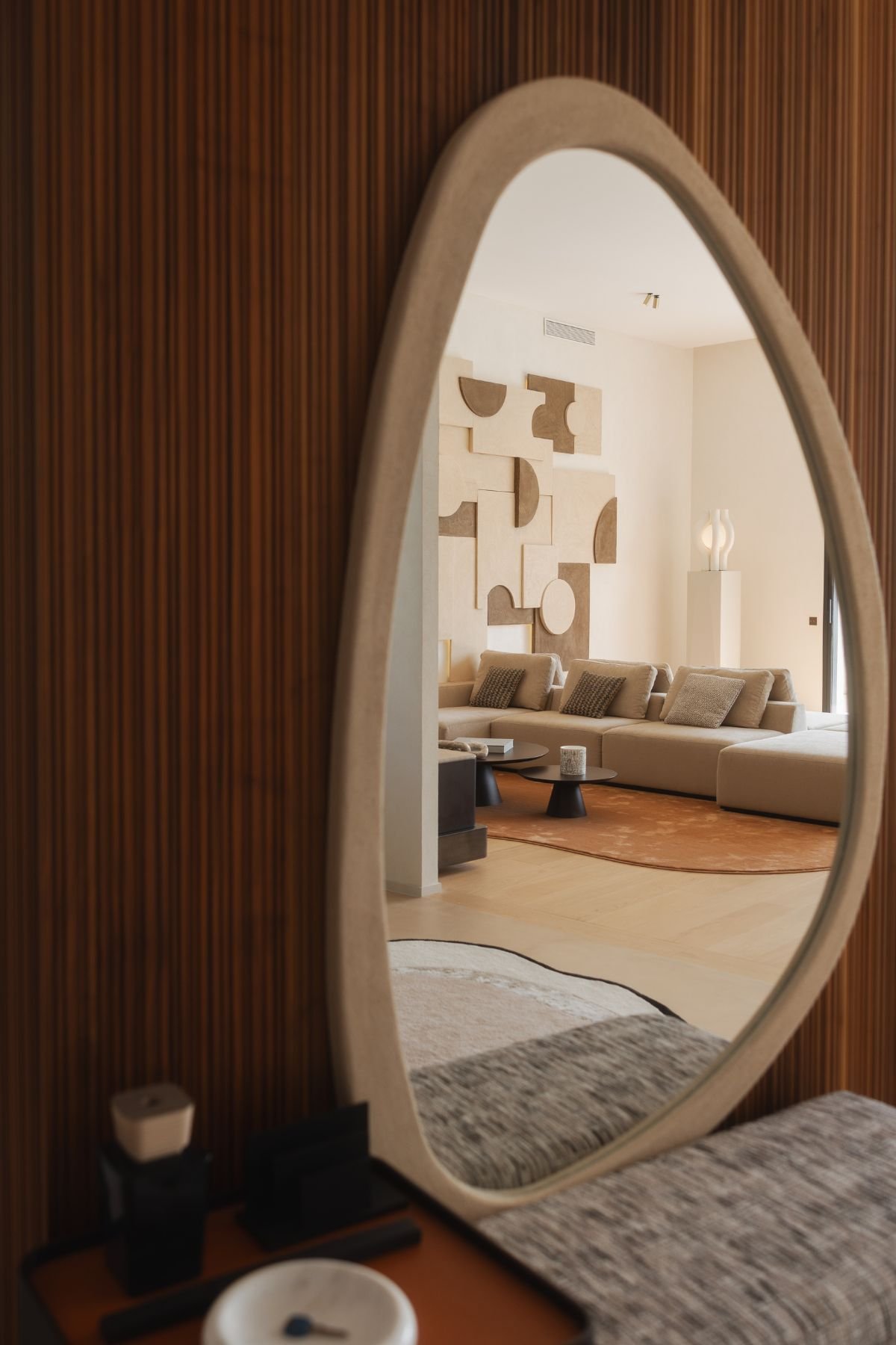 Espelho grande de formato orgânico a refletir a sala de estar moderna e a zona de design de interiores da casa.